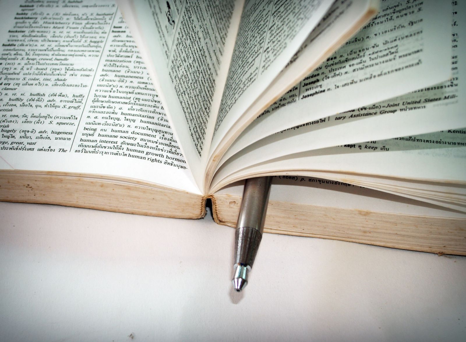 White ballpoint pen resting on open book pages