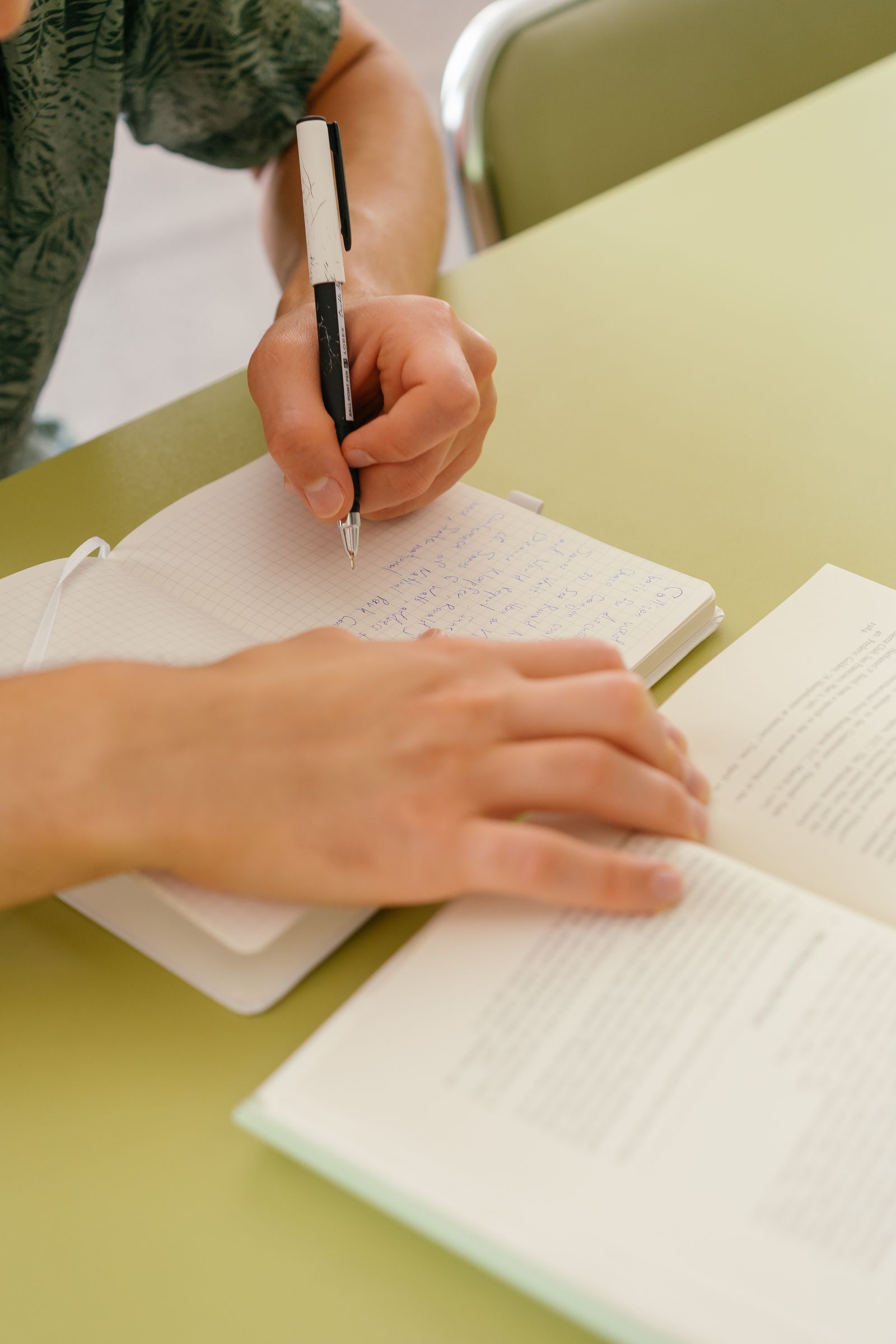 Student writing notes while doing homework at a desk