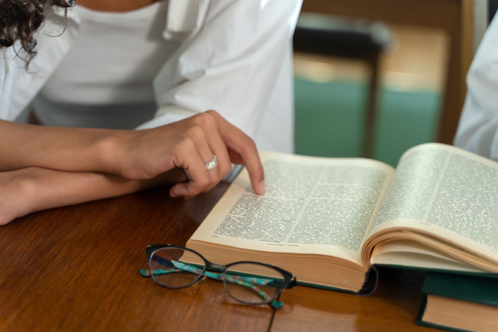 Hand pointing at text in an open book