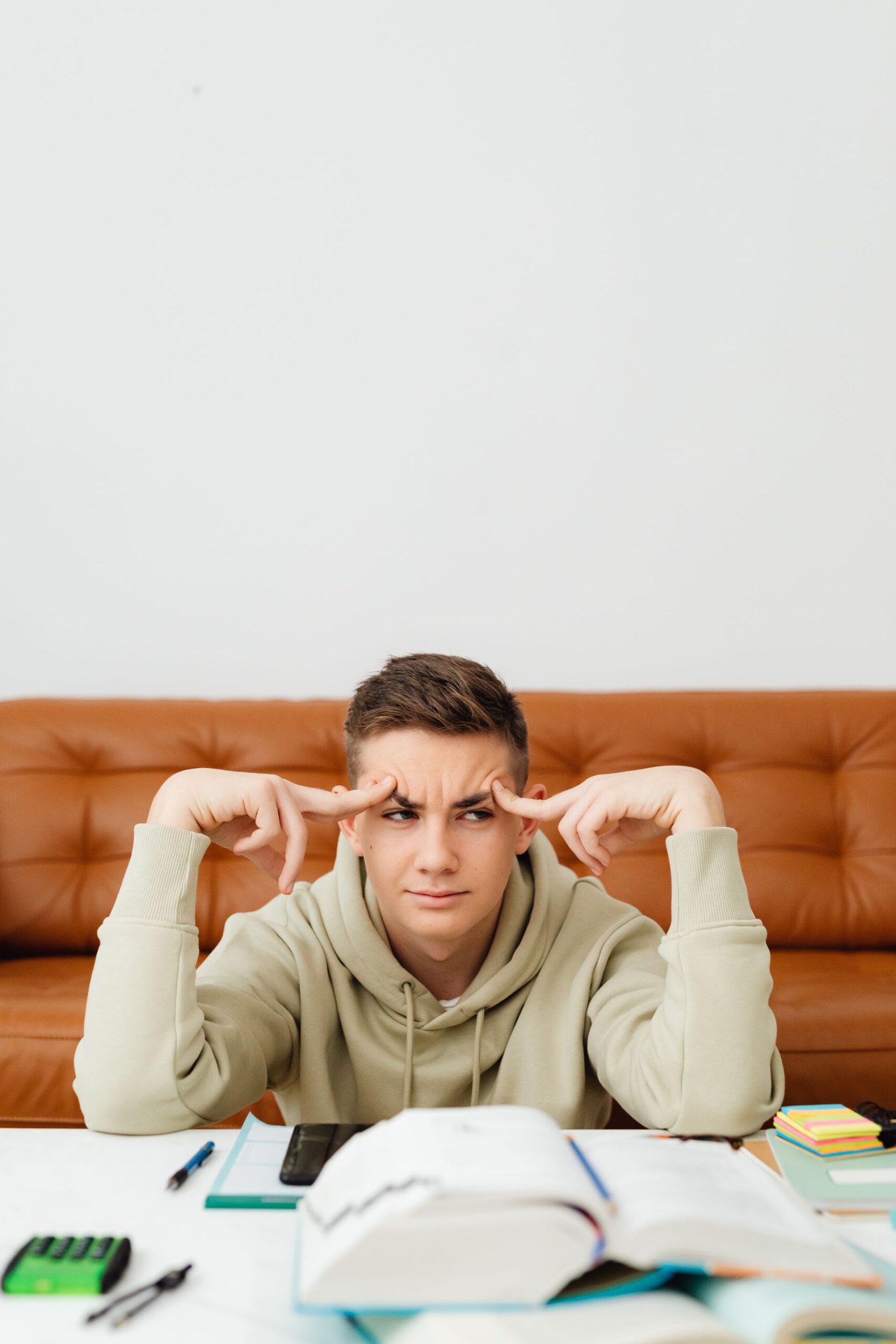 Teenage boy sitting in front of open textbooks looking confused