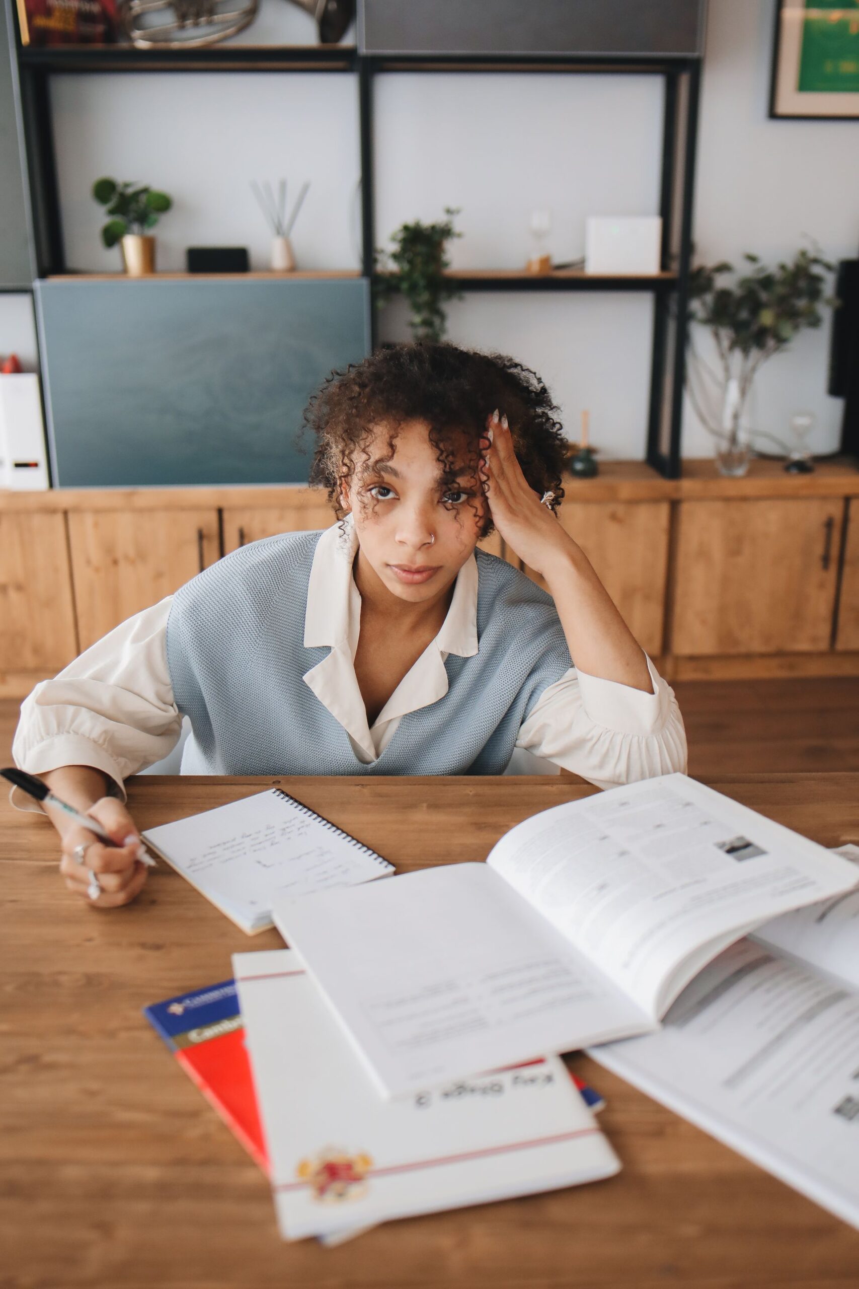 Young woman studying at a desk surrounded by books