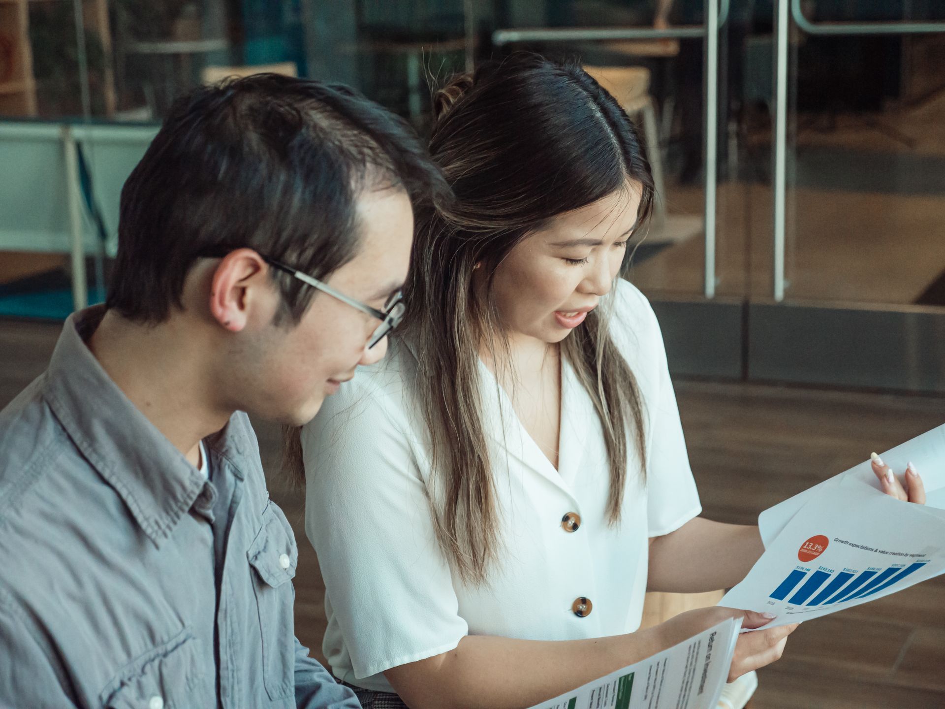 A man and woman holding documents in an office