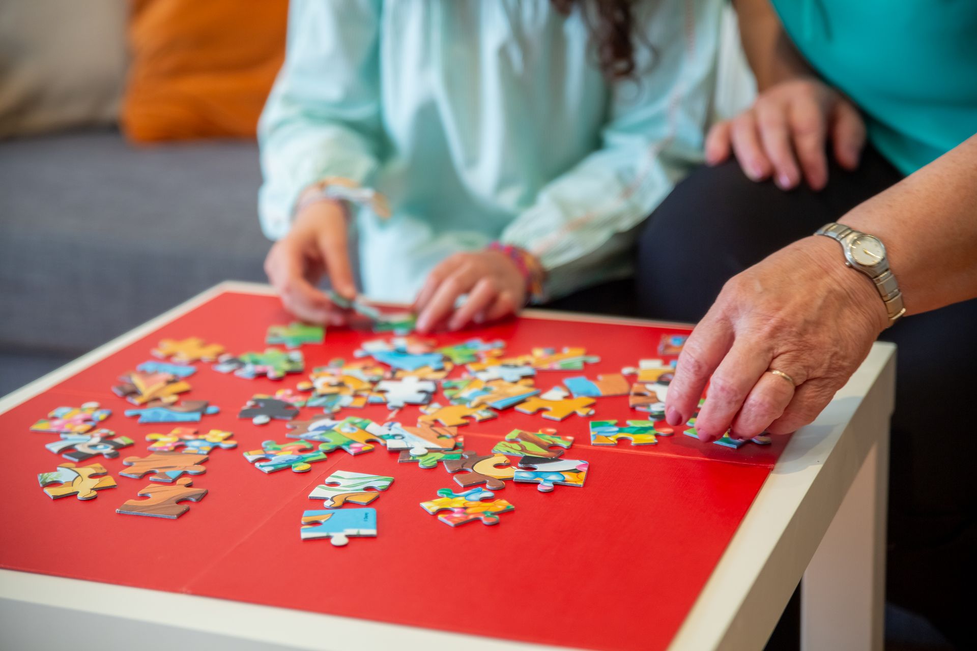 Hands working together on a colorful jigsaw puzzle