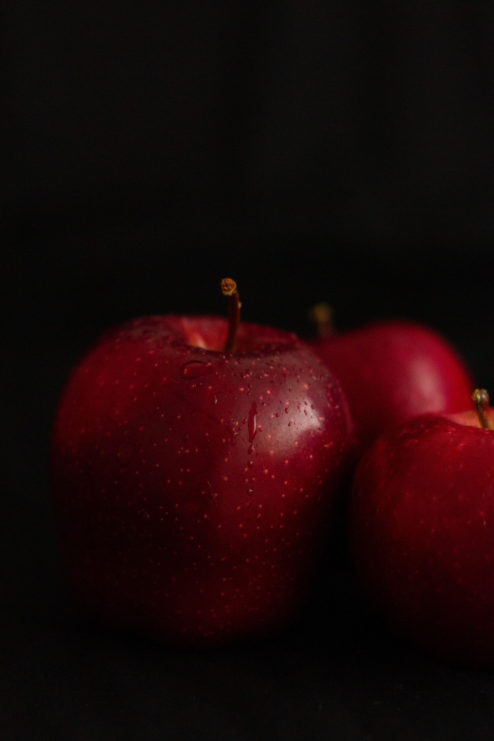 Vibrant red apples with water droplets showing freshness and natural beauty against a dark background.