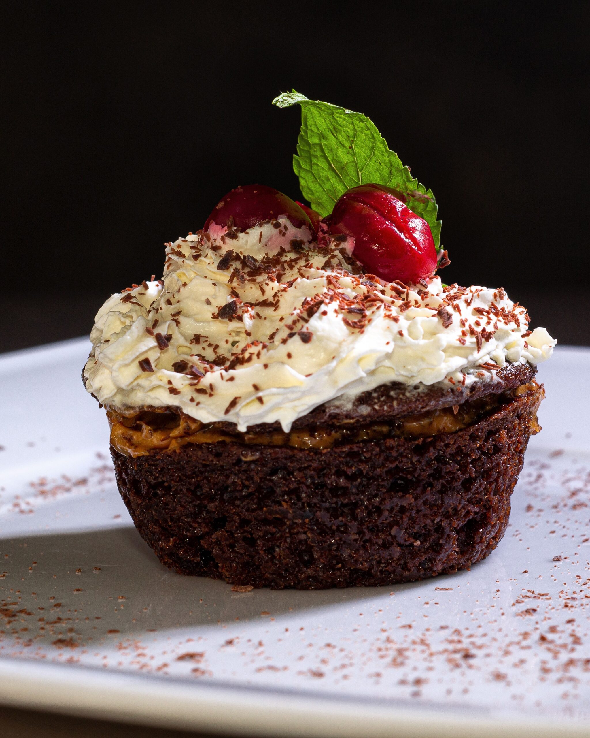 Indulgent chocolate cupcake topped with whipped cream and cherry garnish.