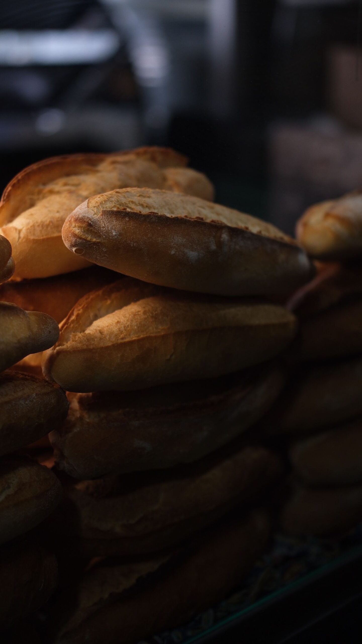 Warmly lit stack of freshly baked bread loaves at a bakery