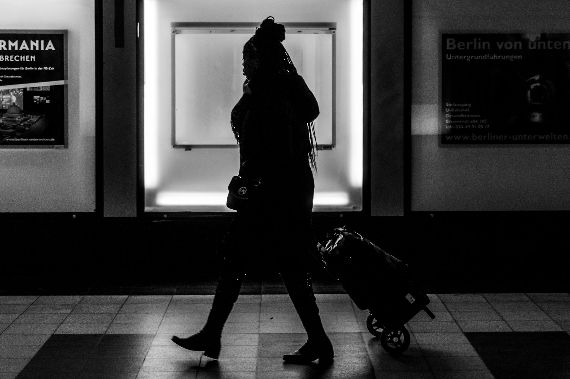 Woman pulling rolling luggage through a Berlin subway station