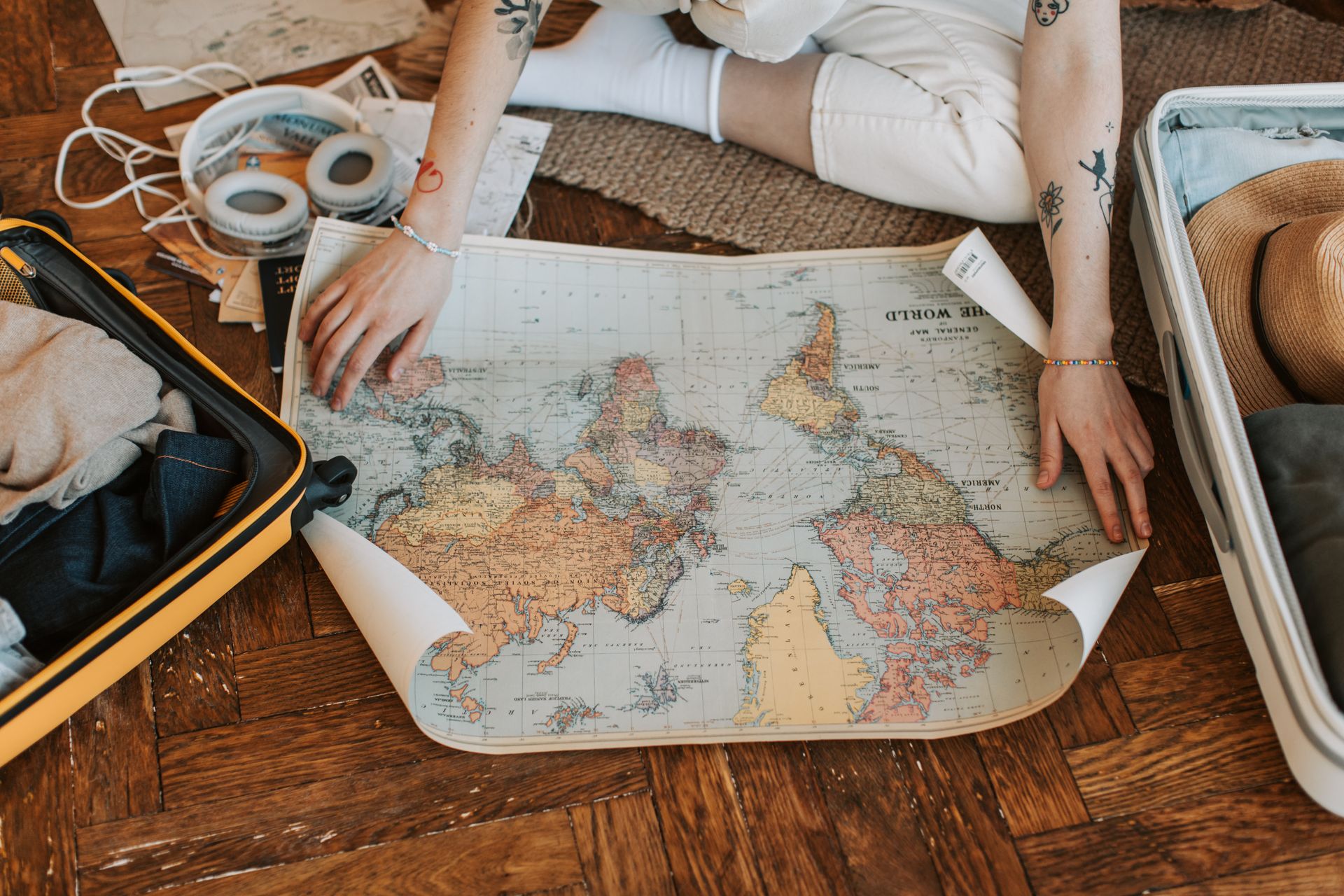 Traveler planning a trip with a world map and packed suitcase