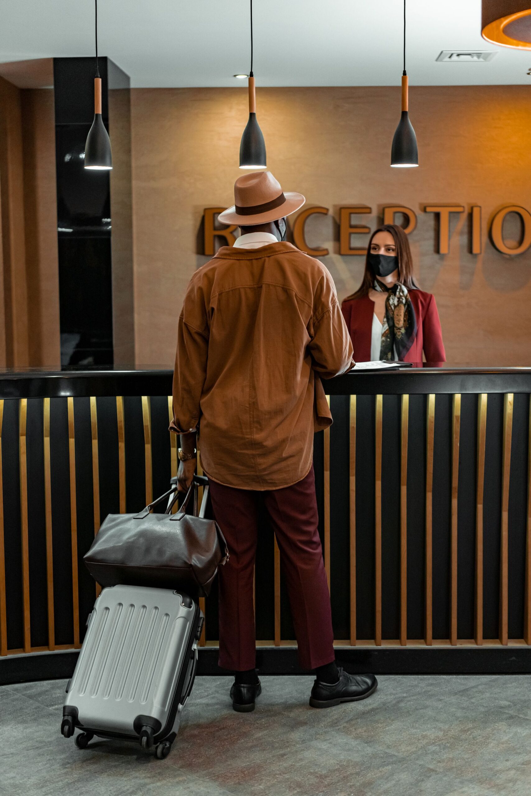 Traveler with luggage checking in at a hotel reception desk