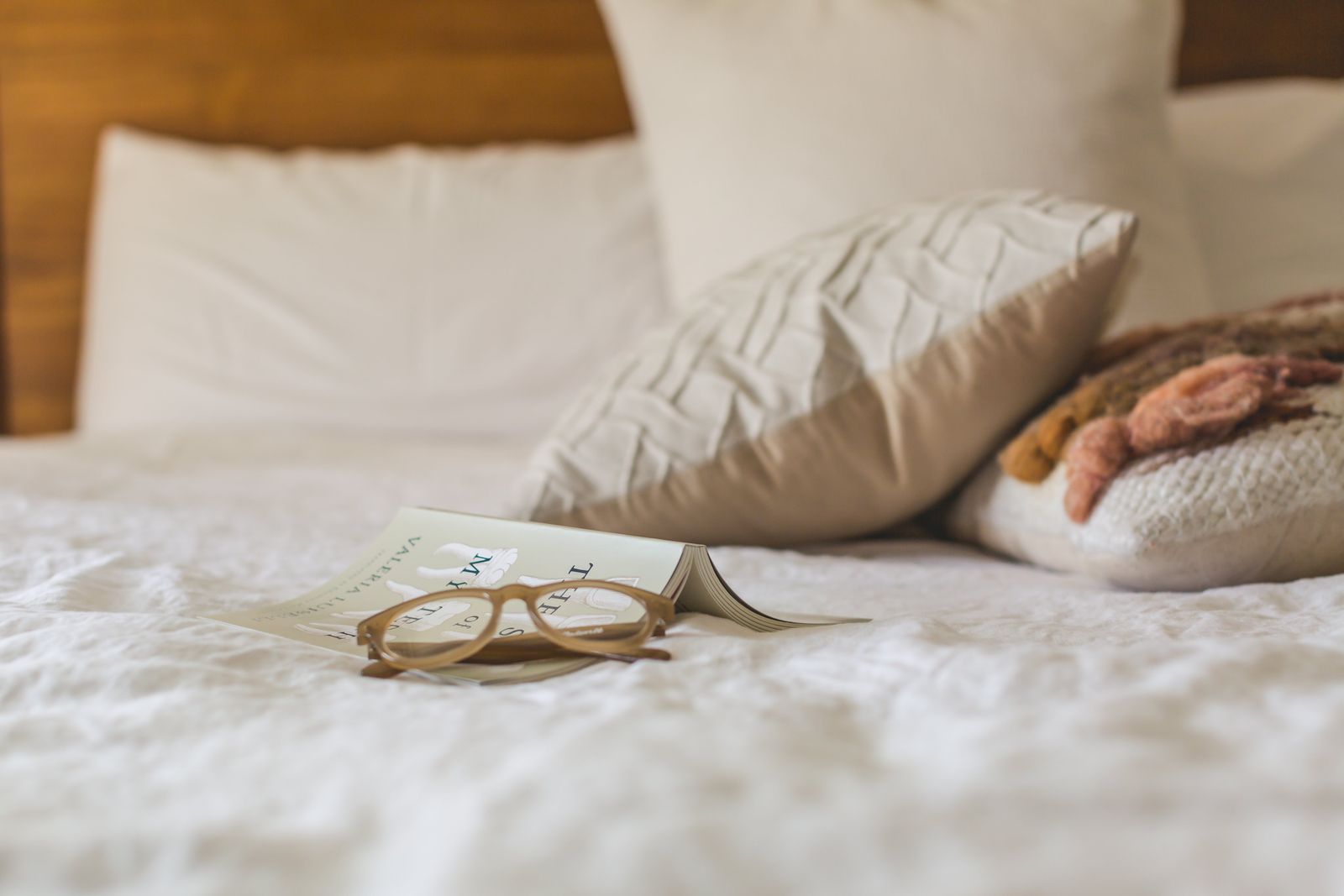 Serene bedroom scene with an open book and reading glasses on a soft bed