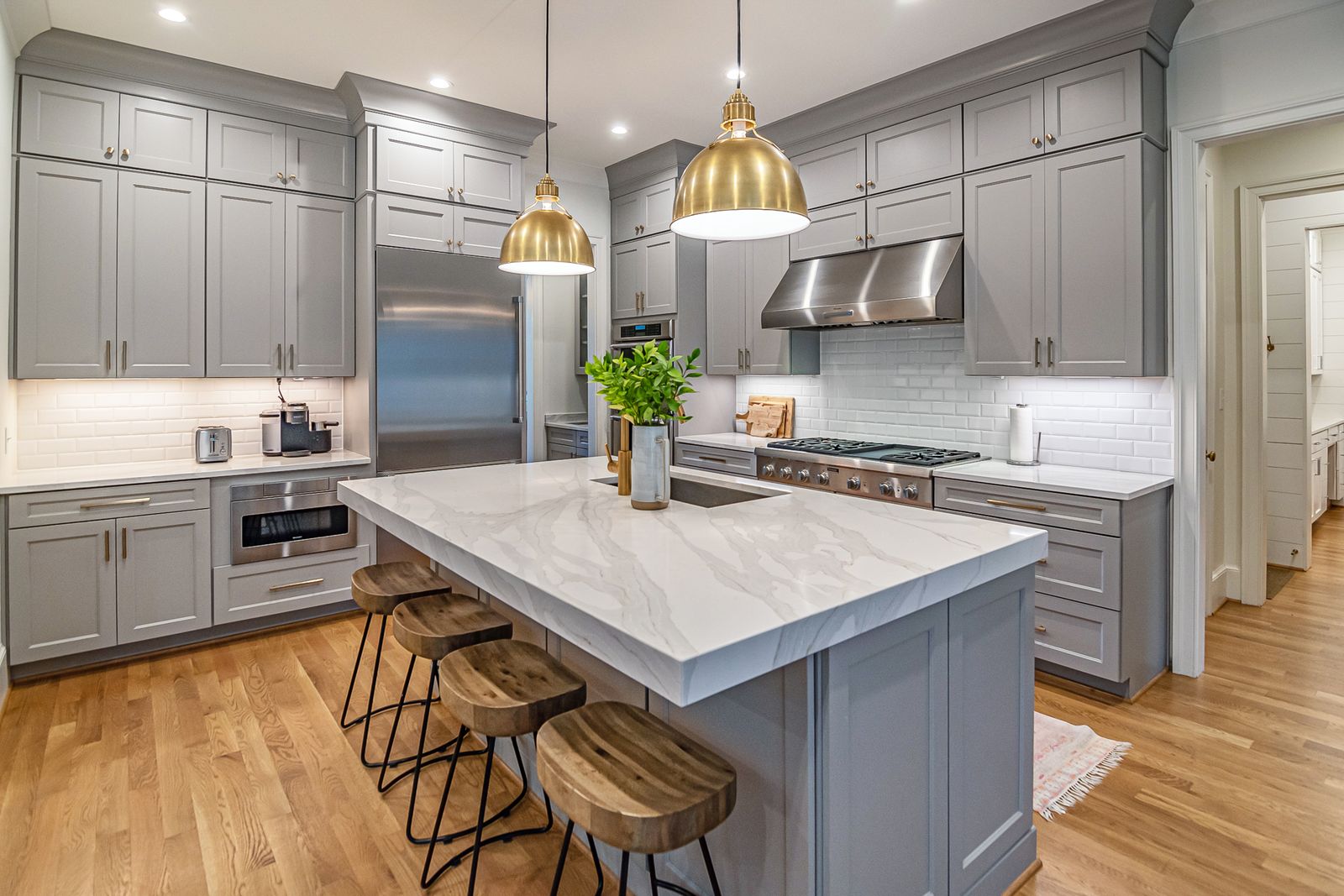 Stylish modern kitchen featuring a large marble island, gold pendant lights, and gray cabinetry
