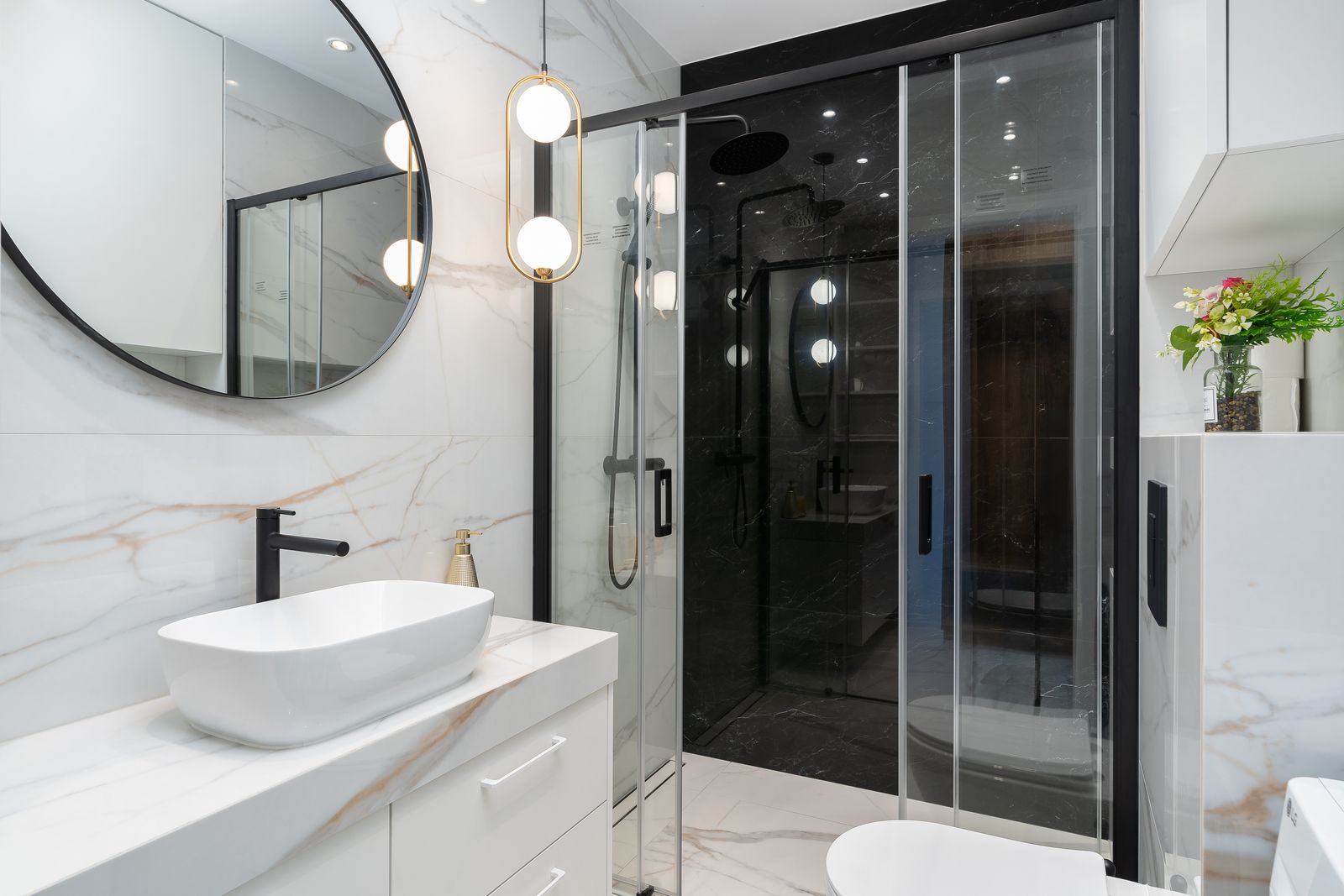 Sleek modern bathroom featuring a marble countertop, stylish circular mirror, and elegant lighting