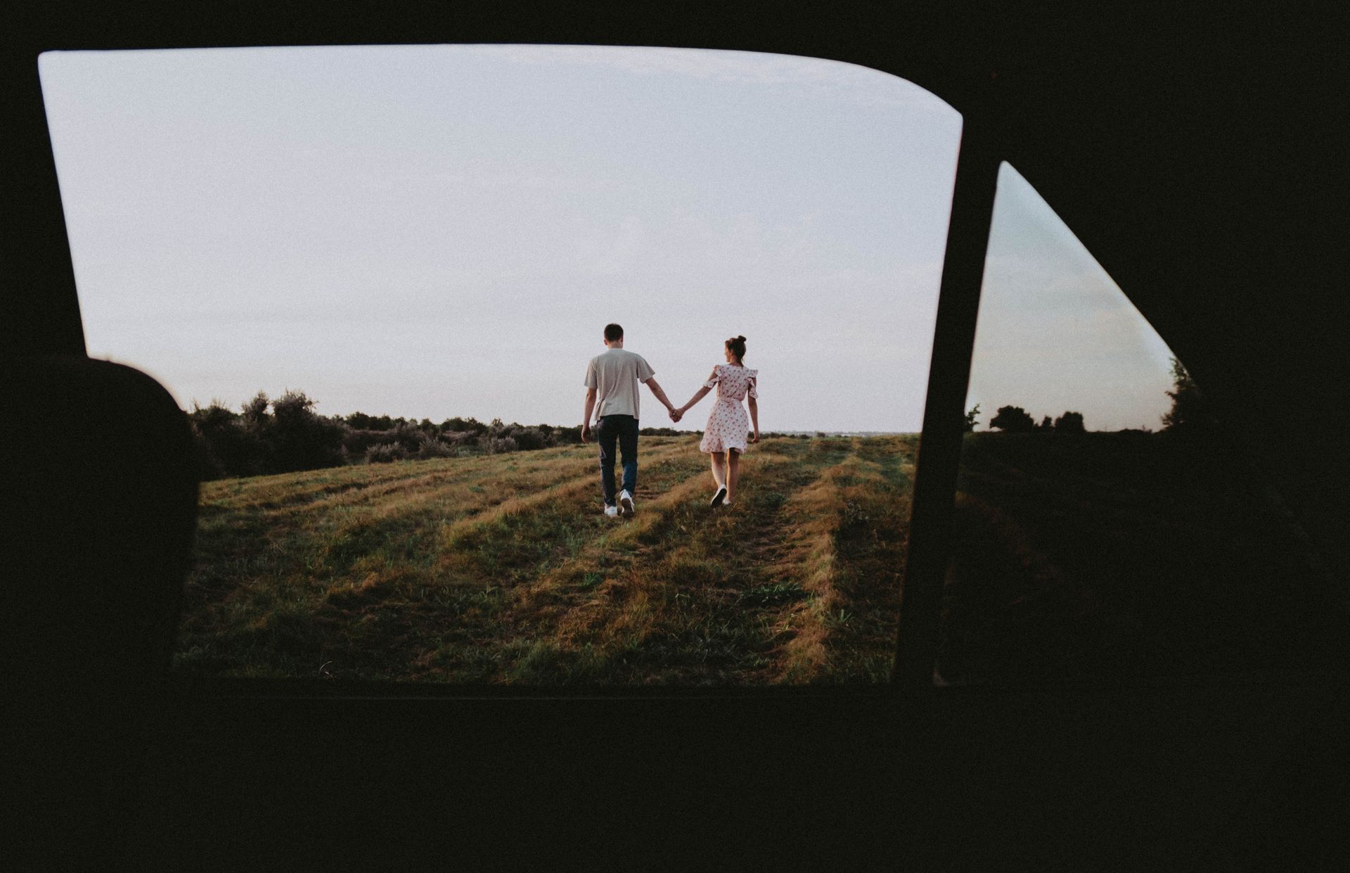 Couple holding hands while walking through a field