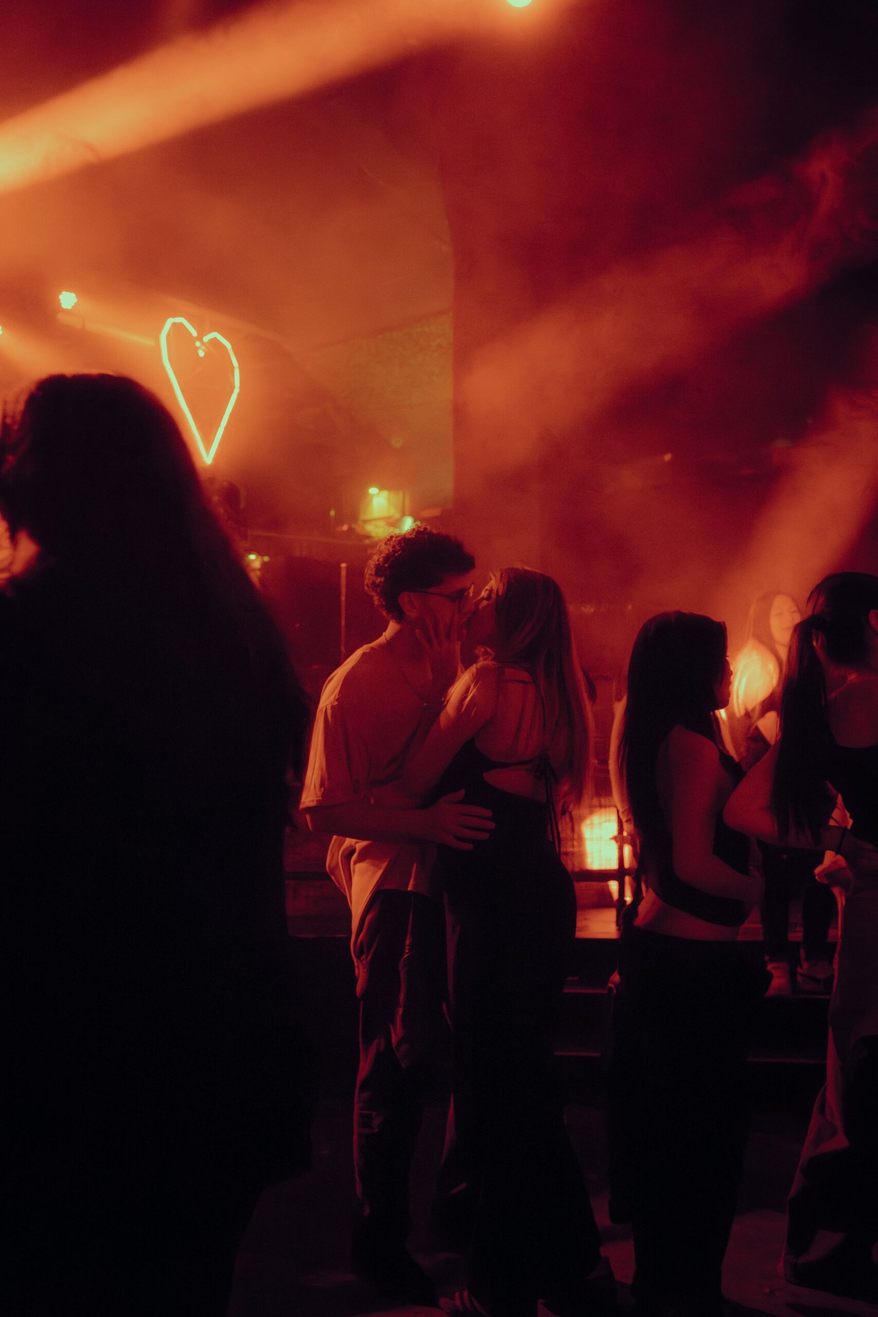 Couple embracing under heart-shaped neon lights at night