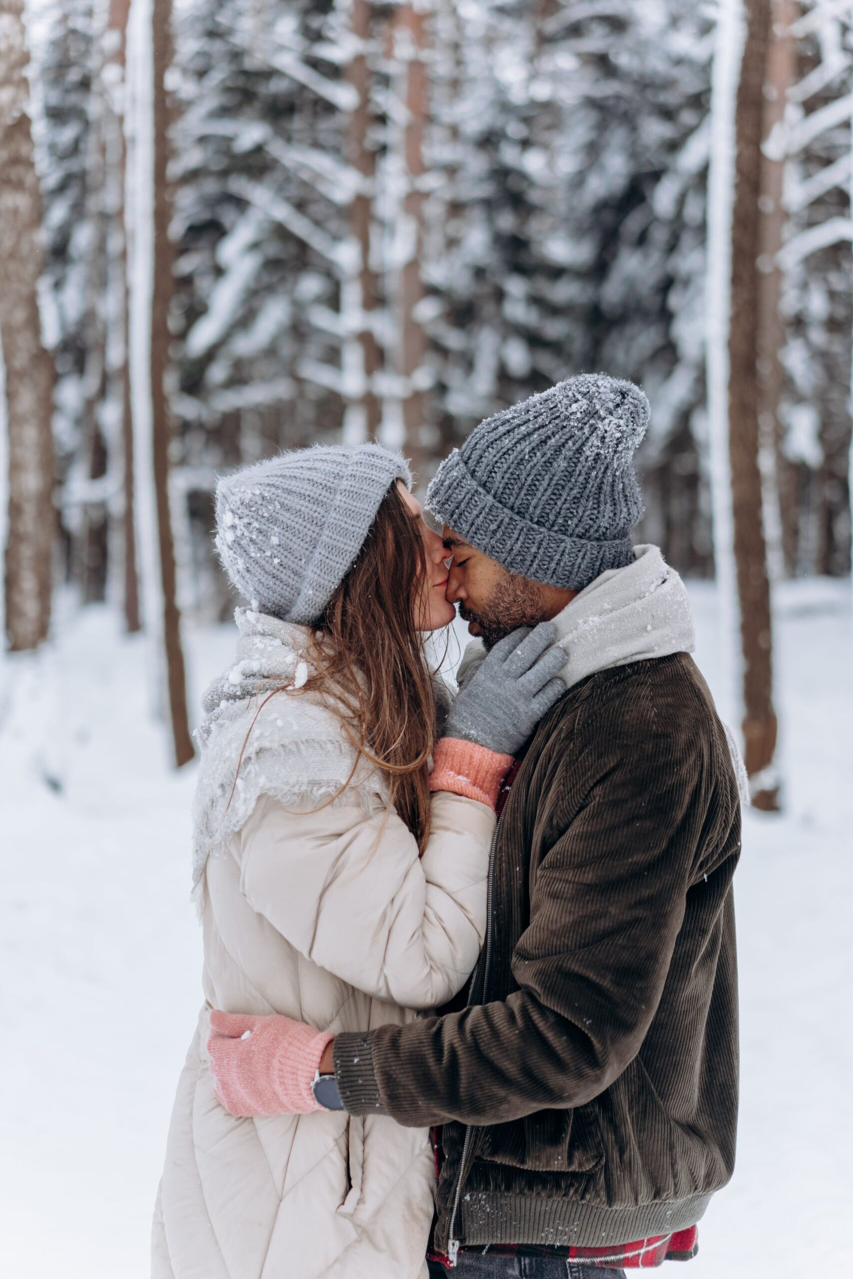 Romantic couple sharing a kiss in a snowy winter forest