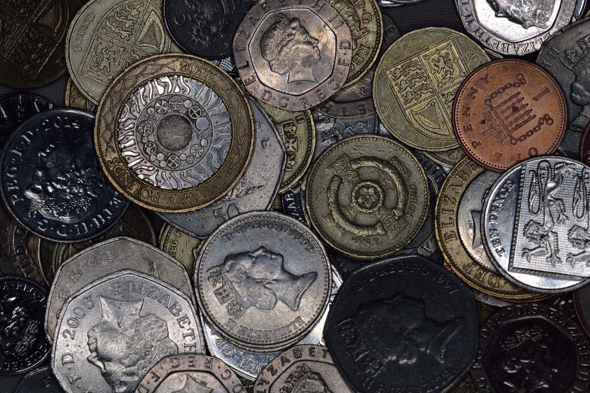 Close-up of various British coins showing diverse designs and denominations