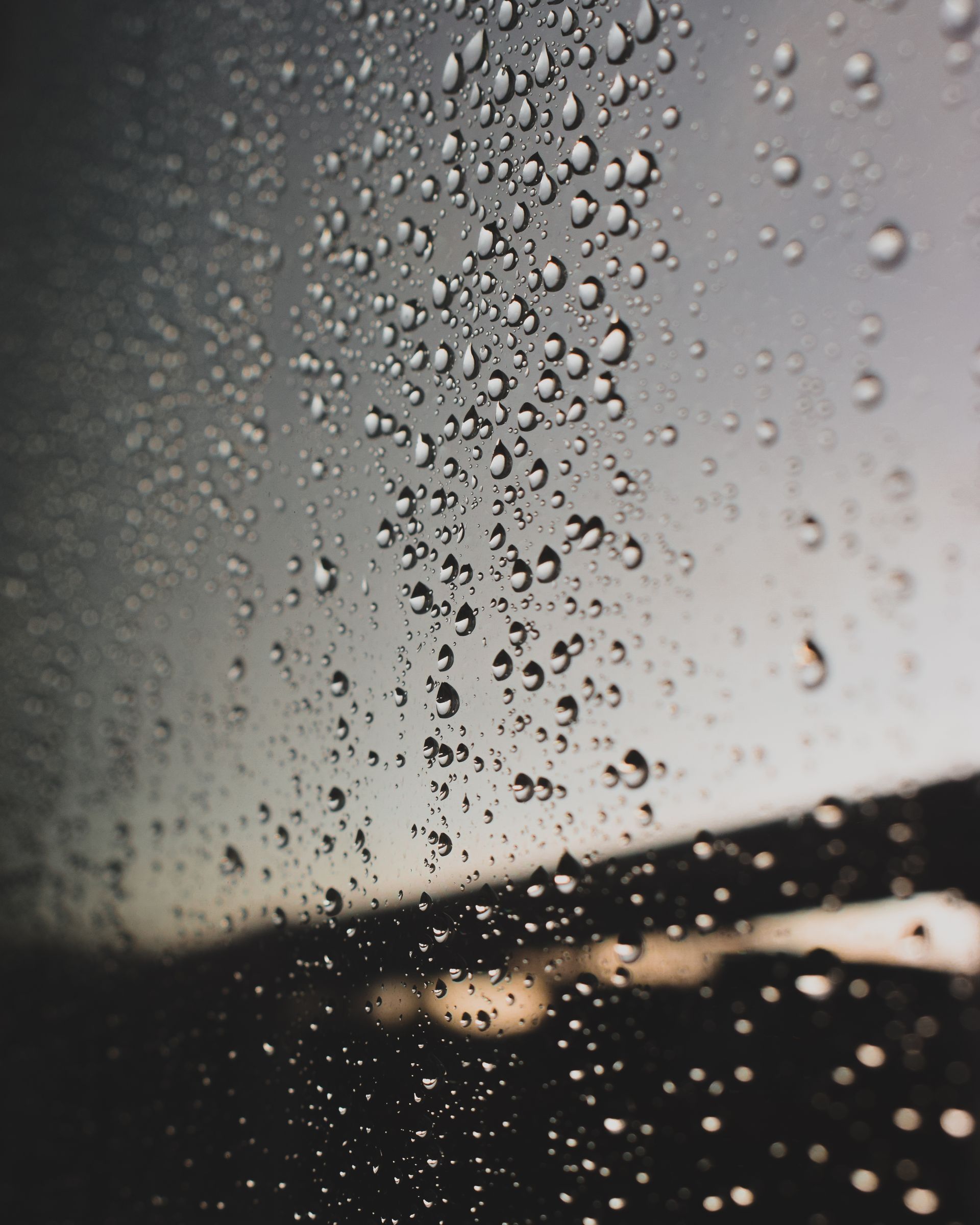 Raindrops on a window with a moody, gloomy evening background