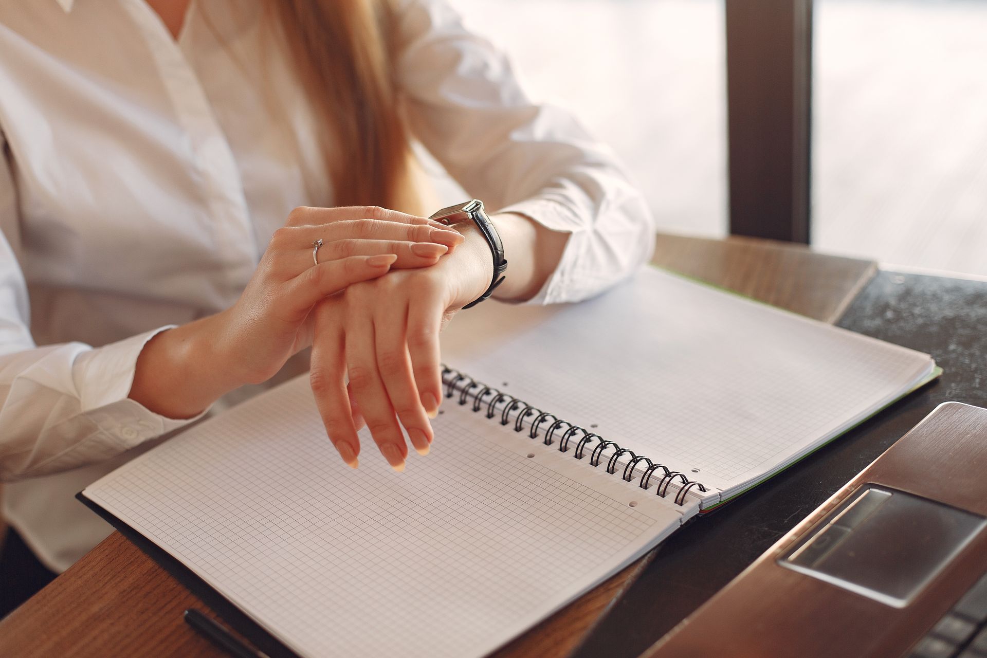 Businesswoman checking the time while working with papers at a desk