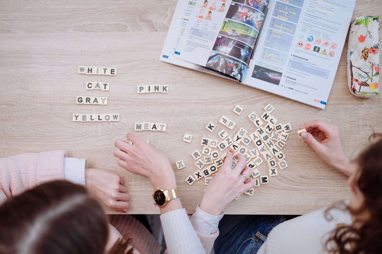Friends studying together with Scrabble tiles and books