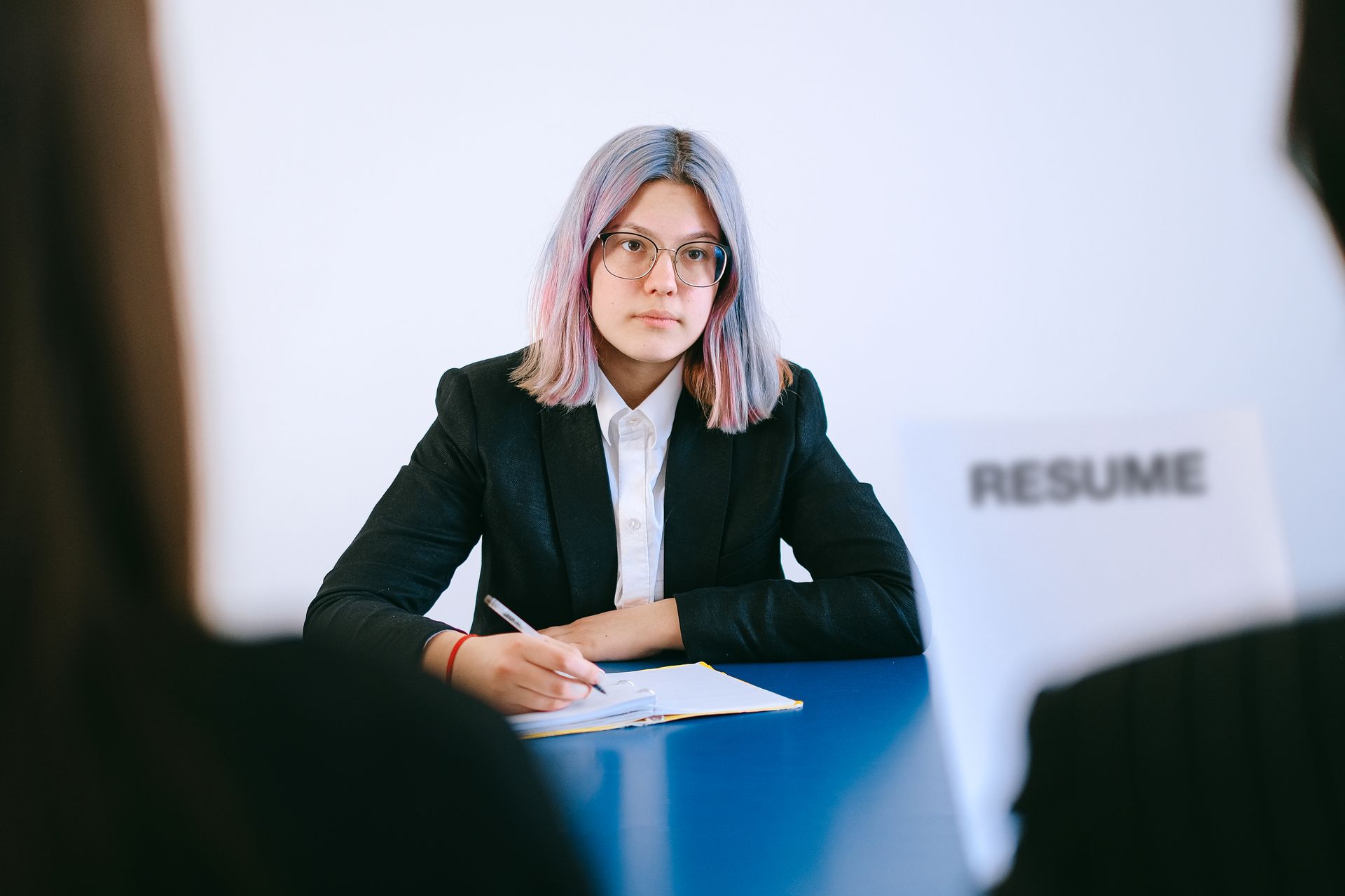 A young woman in a suit during a job interview, writing notes