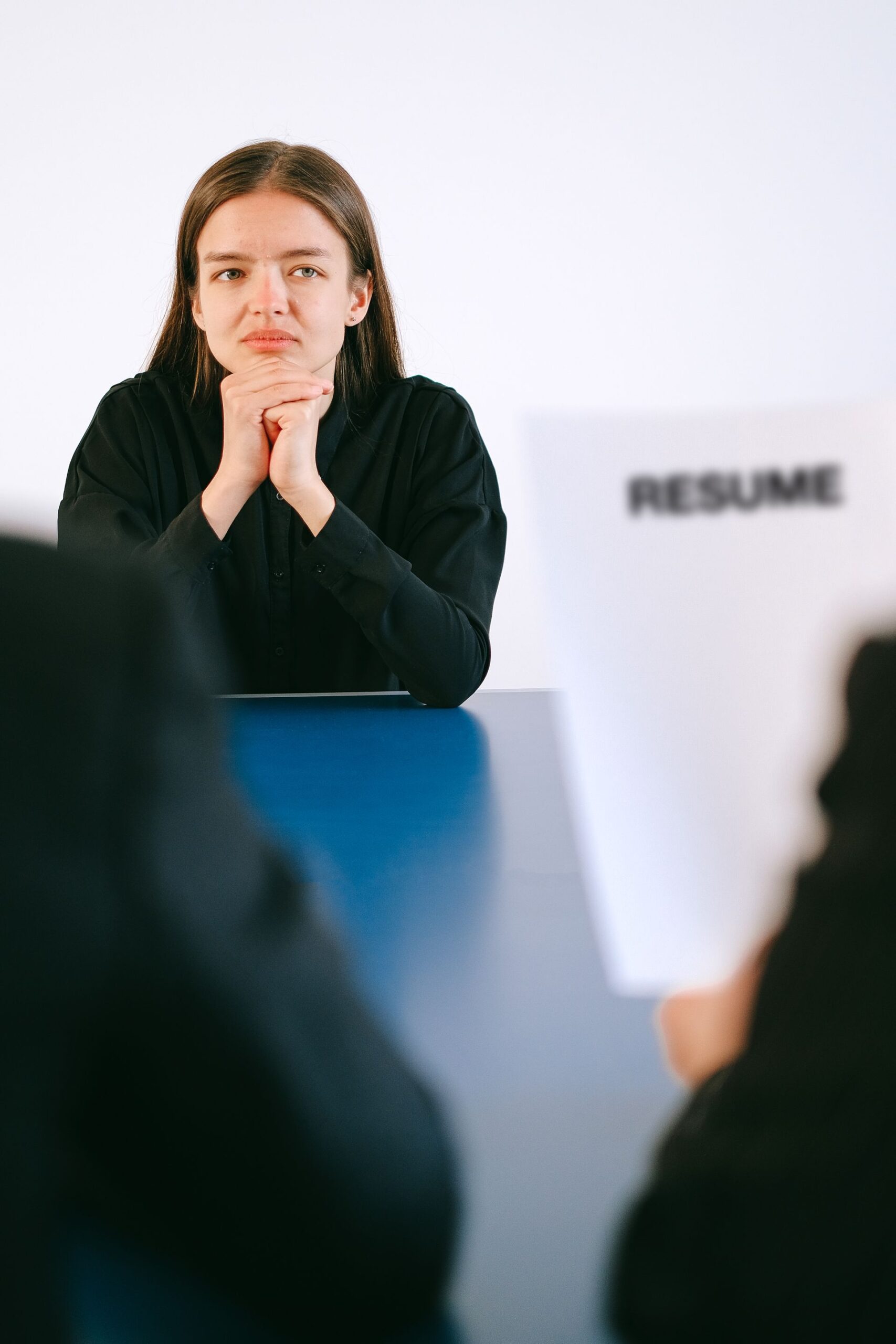 Woman in a serious job interview with resume in focus, sitting at a table