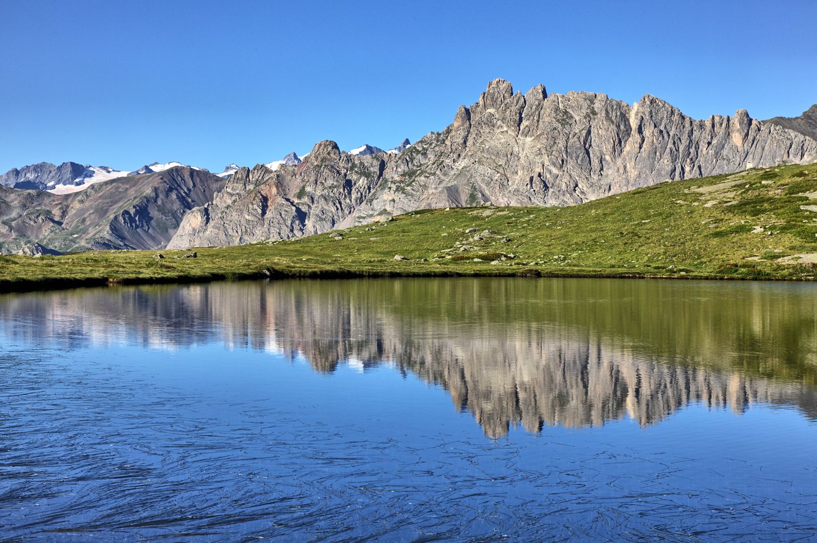 Steep rocky Alps rising above a mountain lake