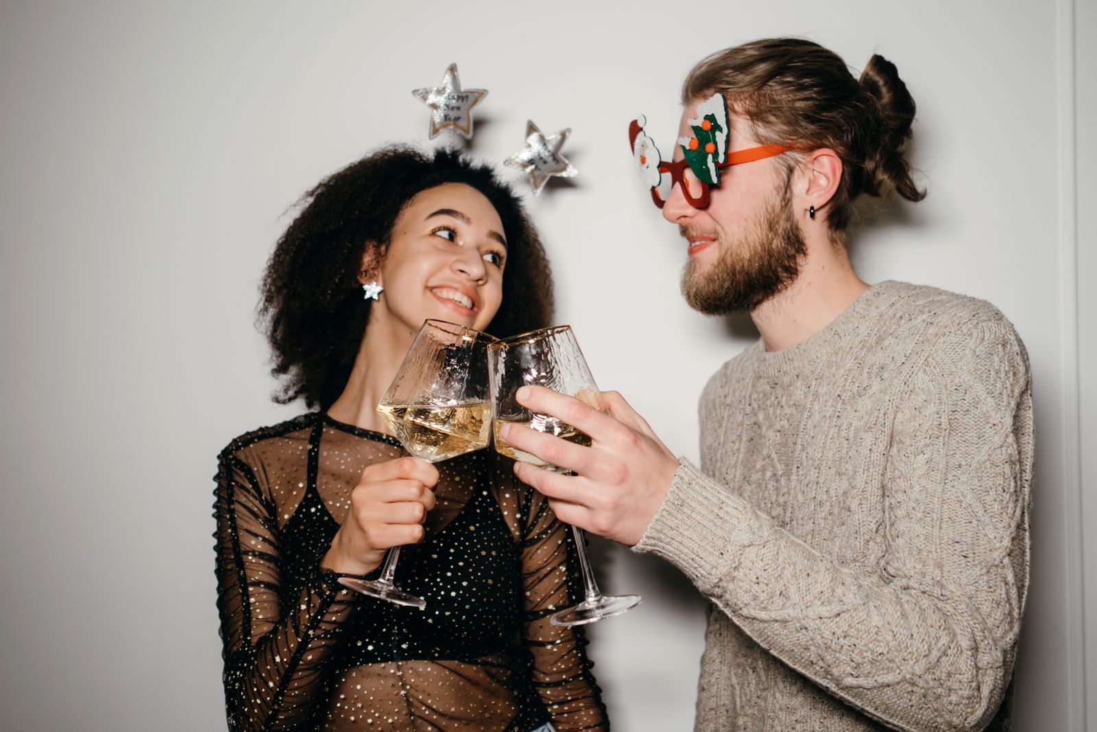 Couple toasting with wine glasses wearing New Year party accessories