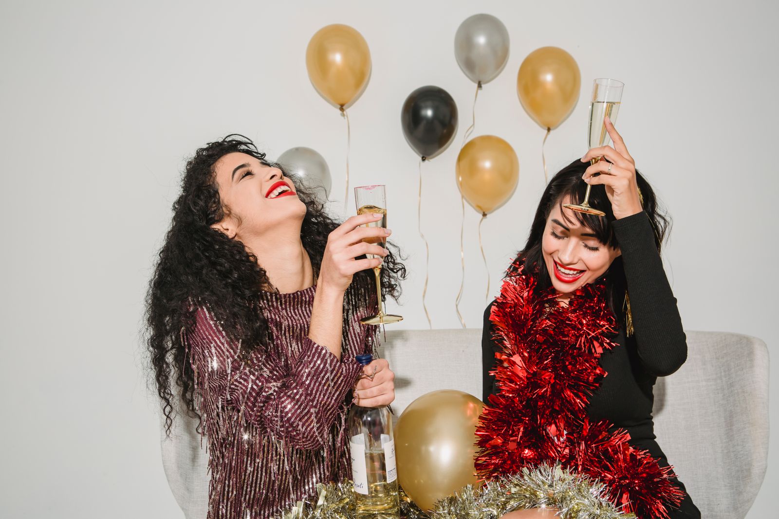 Friends celebrating New Year's Eve indoors with champagne and balloons