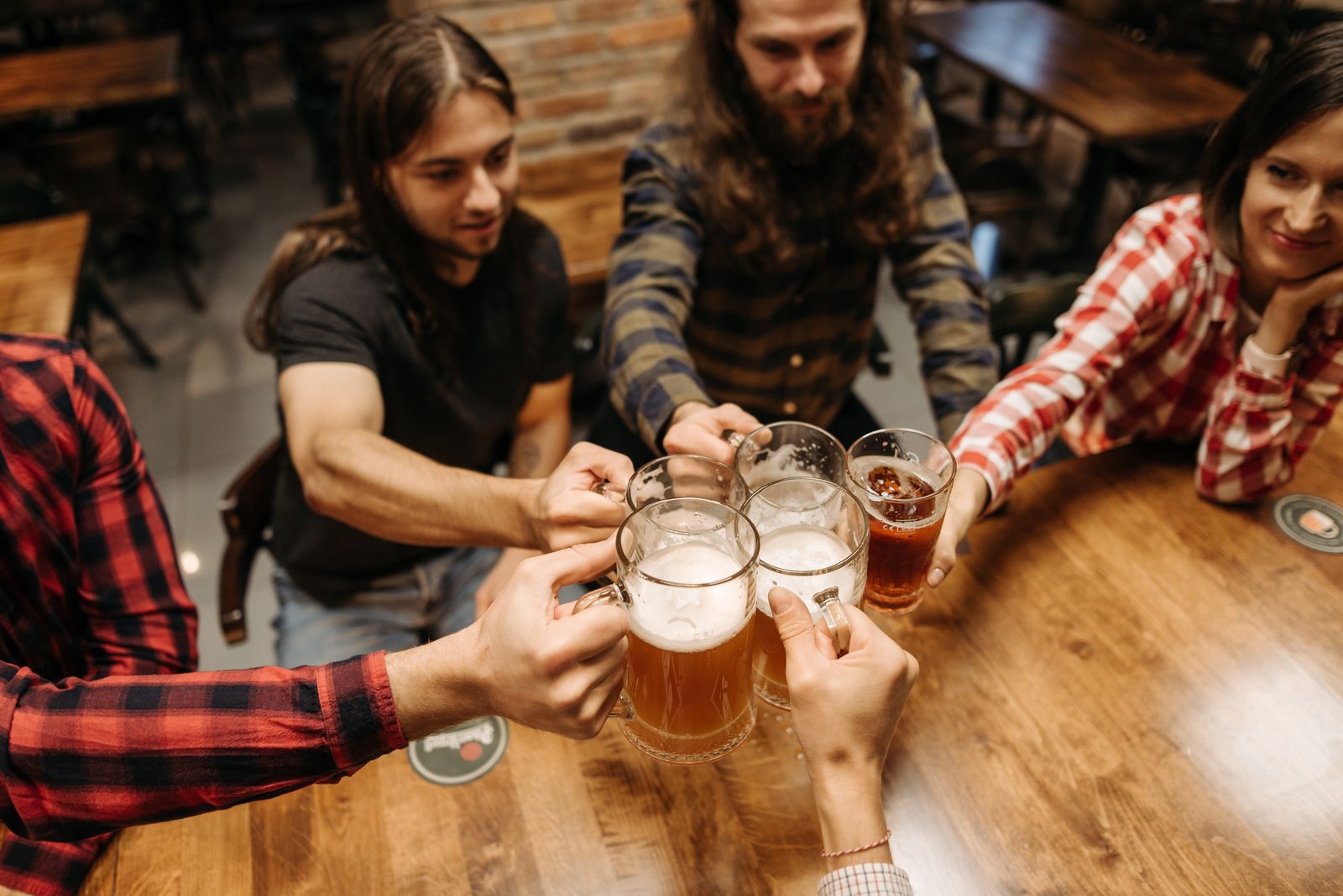 Friends toasting with beer mugs at a cozy bar, Prost