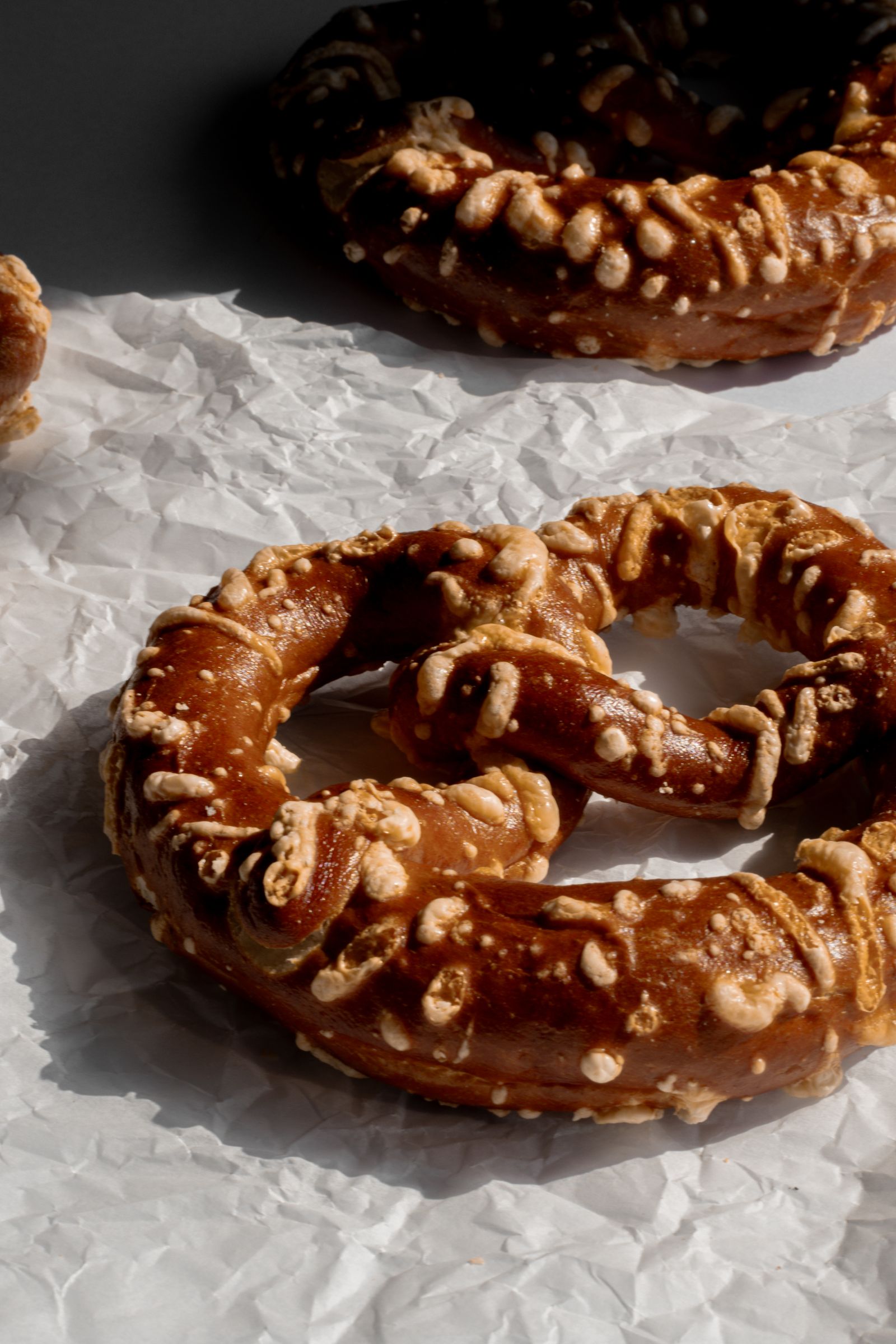 Golden-brown baked pretzels with salt crystals on parchment paper