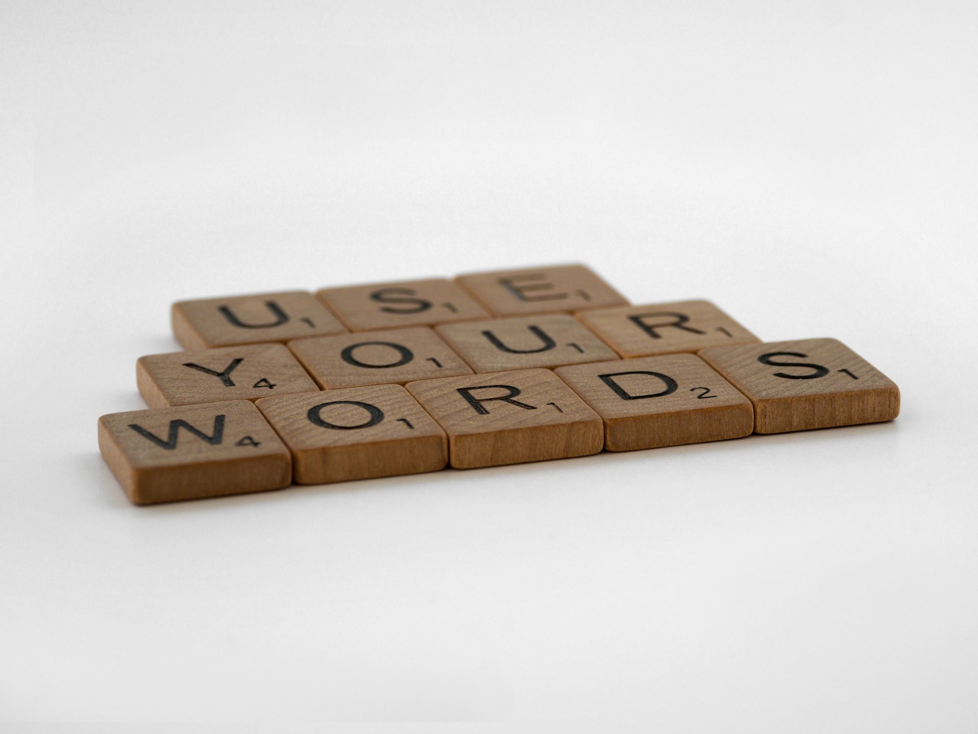 Wooden letter tiles spelling Use Your Words on a white background