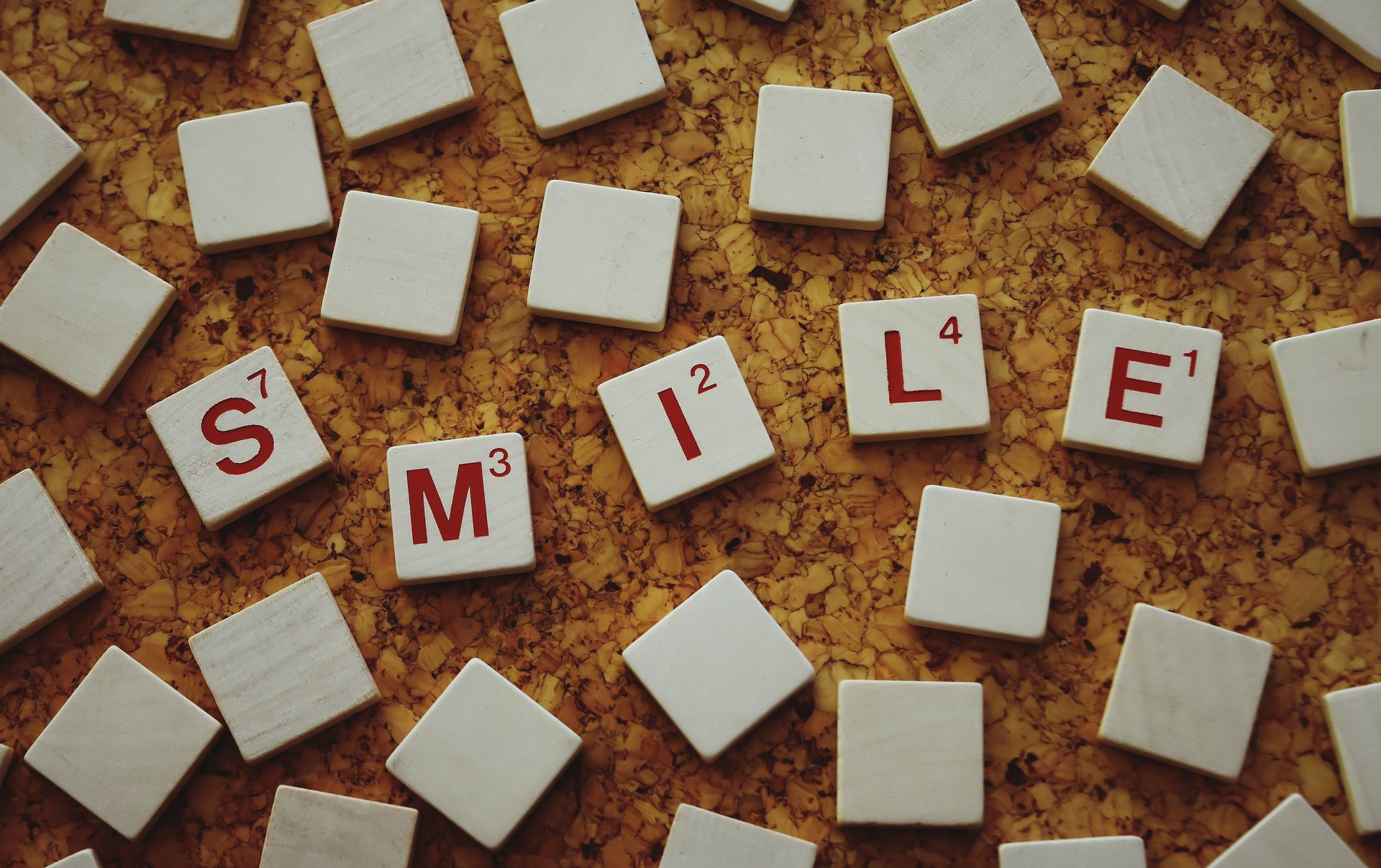Scrabble tiles spelling Smile on a textured corkboard