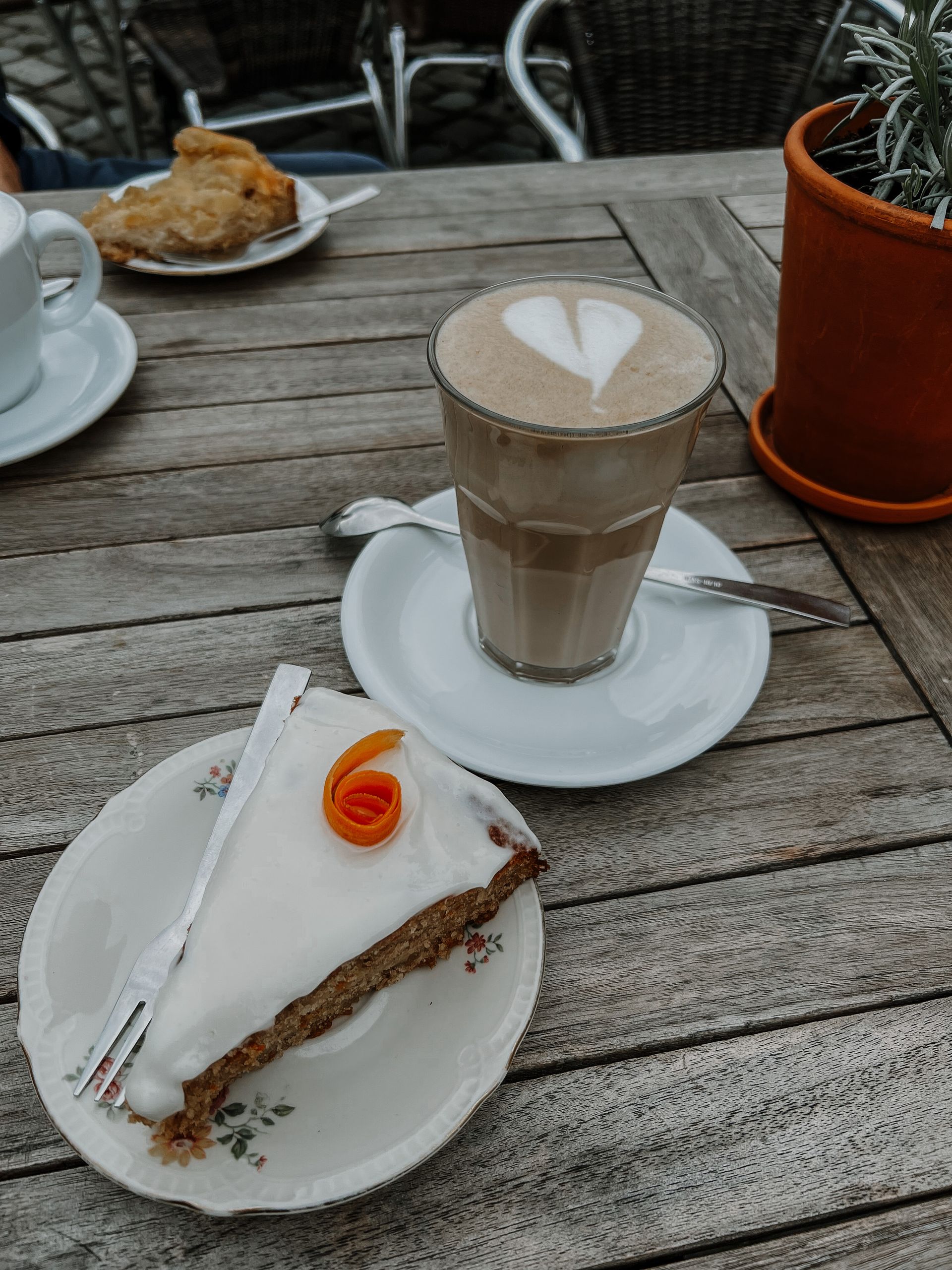 Latte and dessert on a rustic wooden café table outdoors
