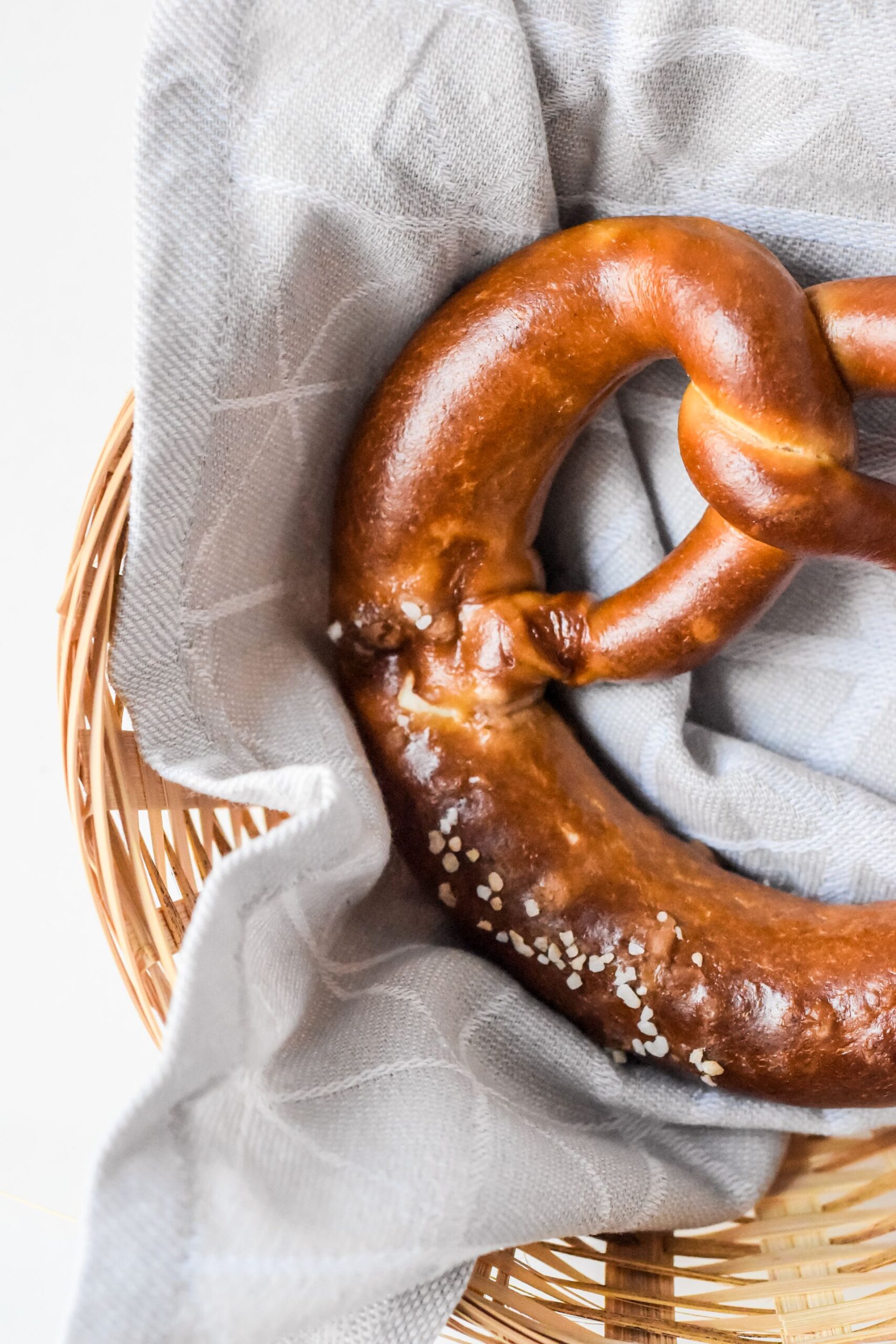 Salted pretzel in a wicker basket with linen cloth