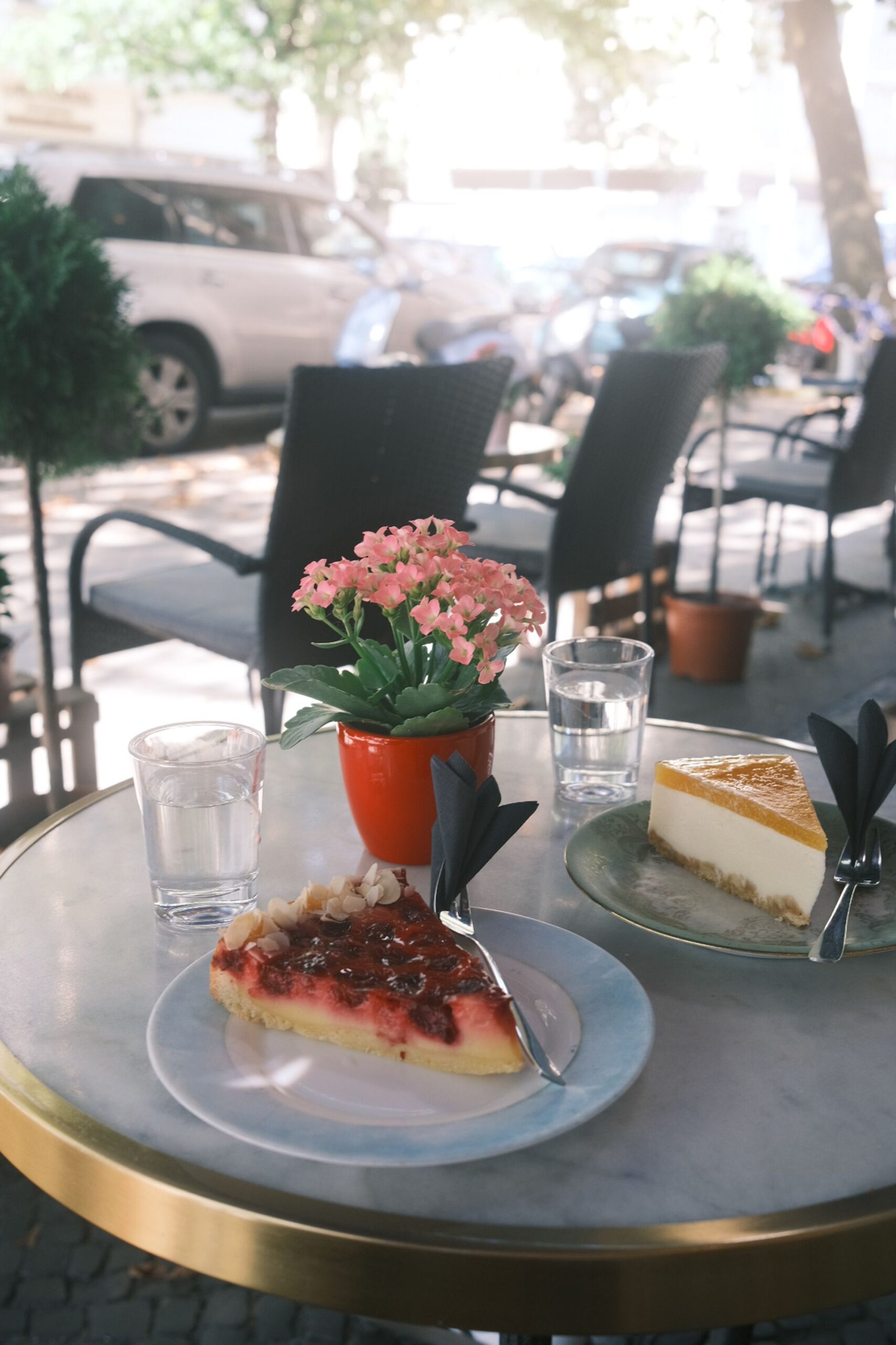 Outdoor café table with cakes and fresh flowers on a sunny day