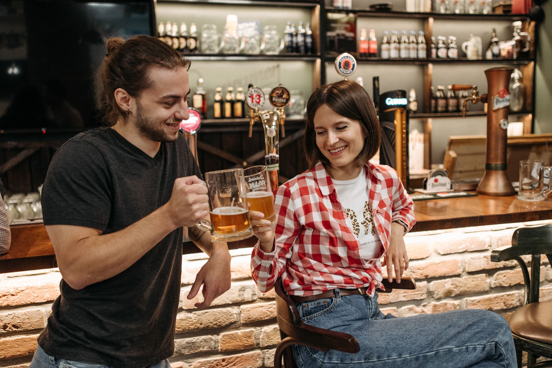 Man and woman drinking beer together at a lively bar