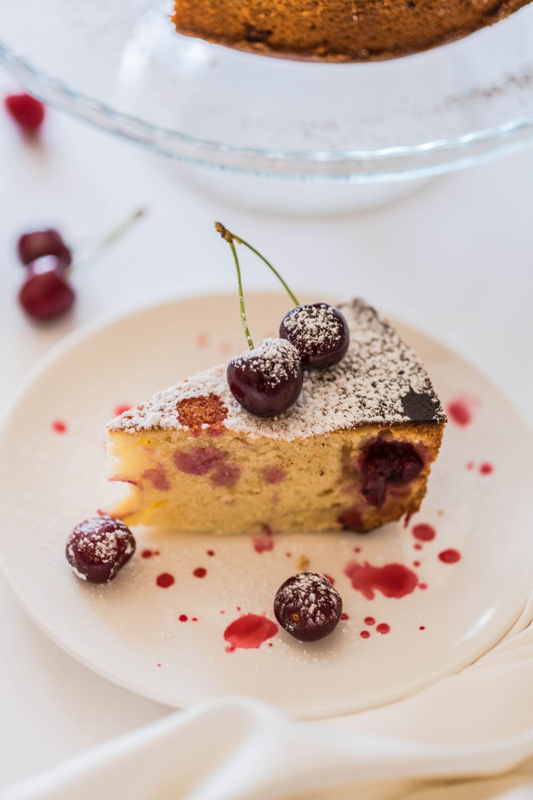 Slice of cherry yogurt cake with powdered sugar on a plate