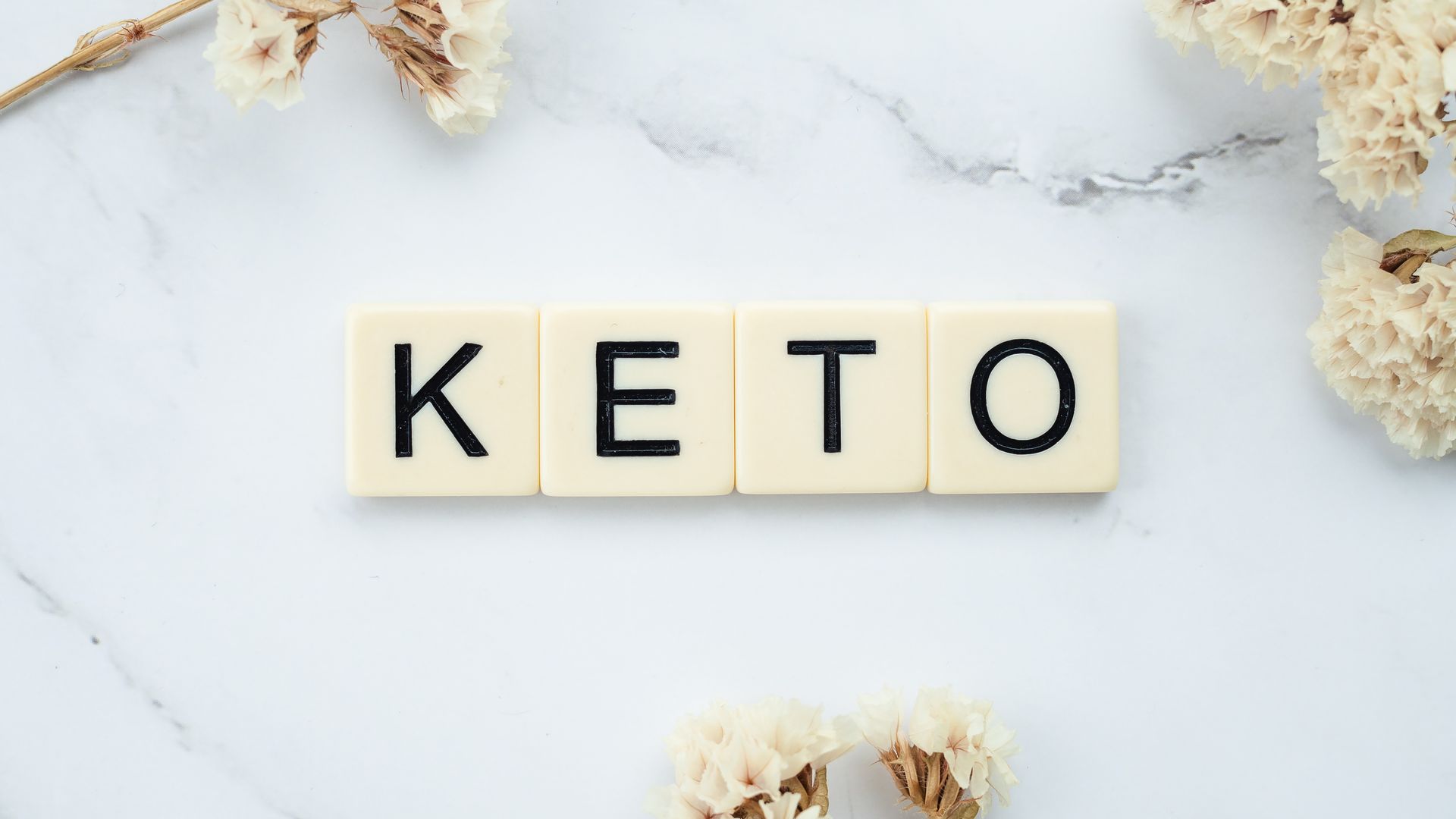 Scrabble tiles surrounded by white flowers on marble