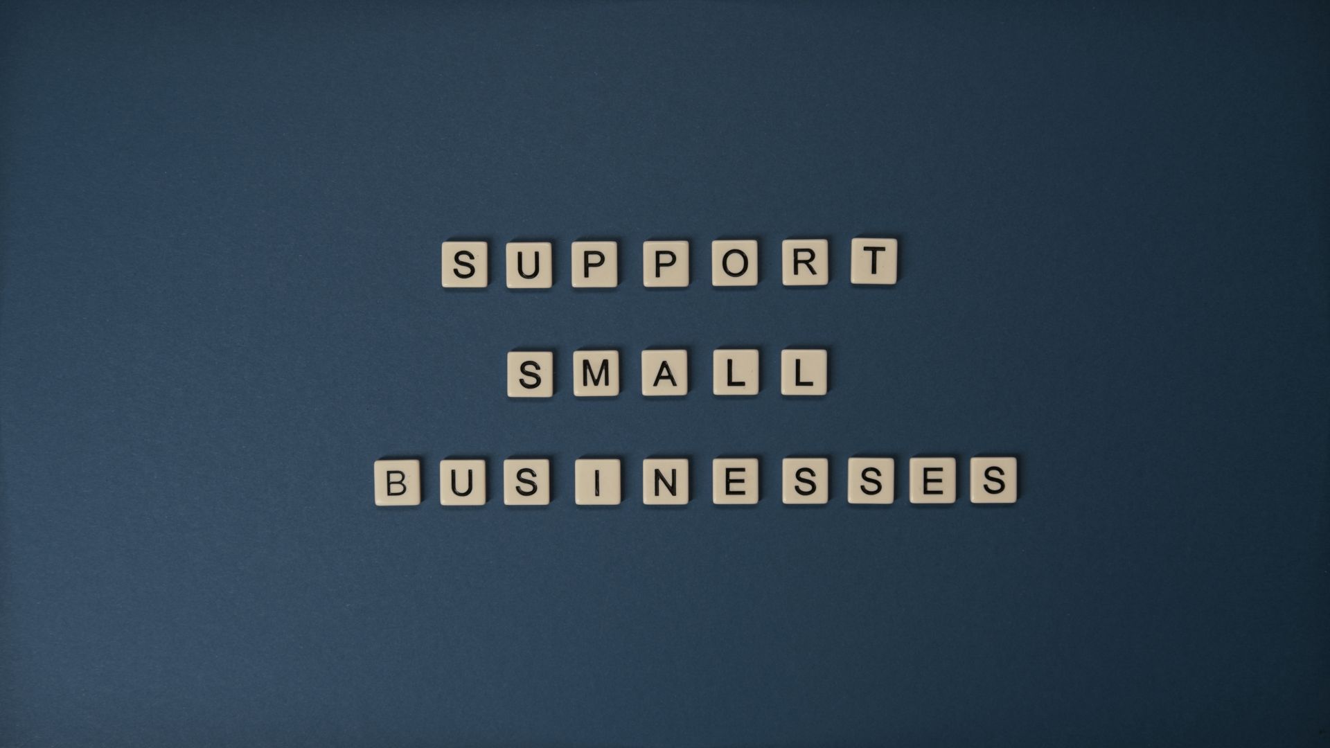 Letter tiles spelling Support Small Businesses on blue