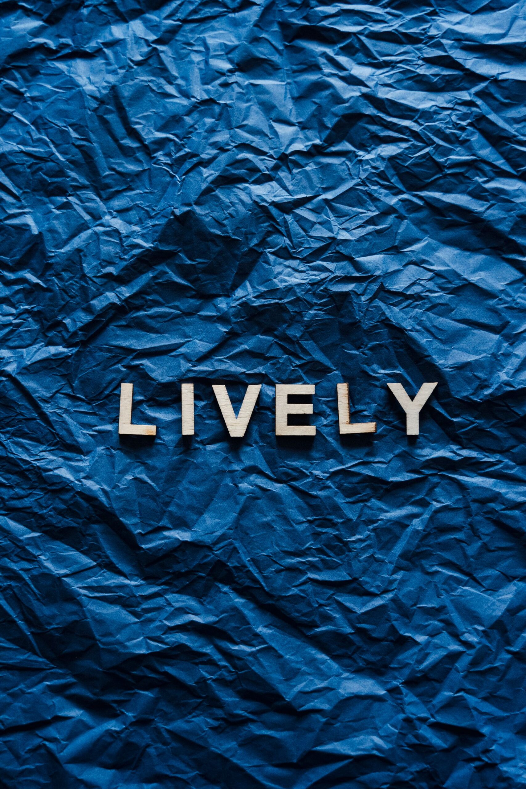 Letter tiles spelling LIVELY on blue fabric