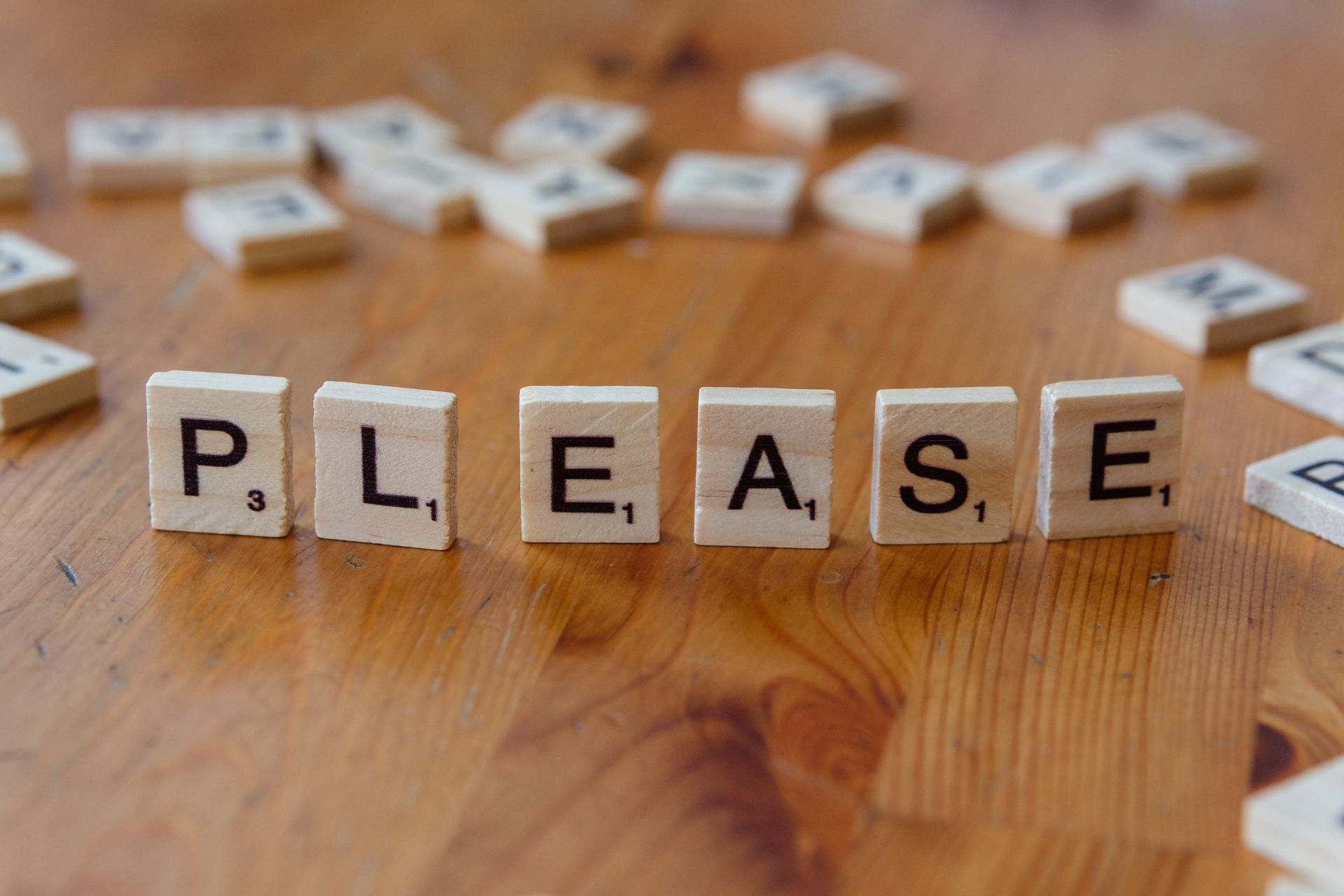 Scrabble tiles spelling Please on a wooden table