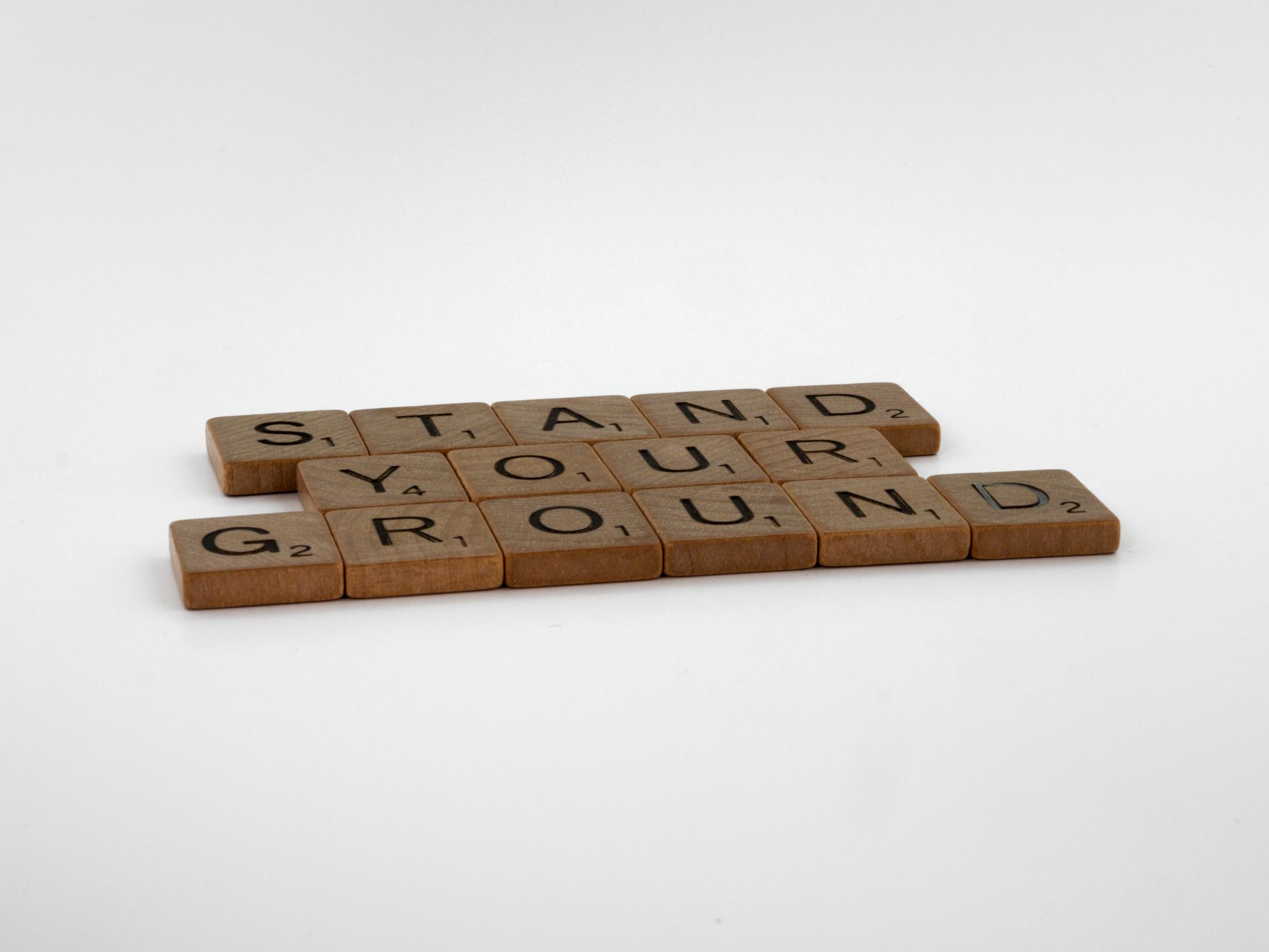 Scrabble tiles spelling Stand Your Ground on a white surface