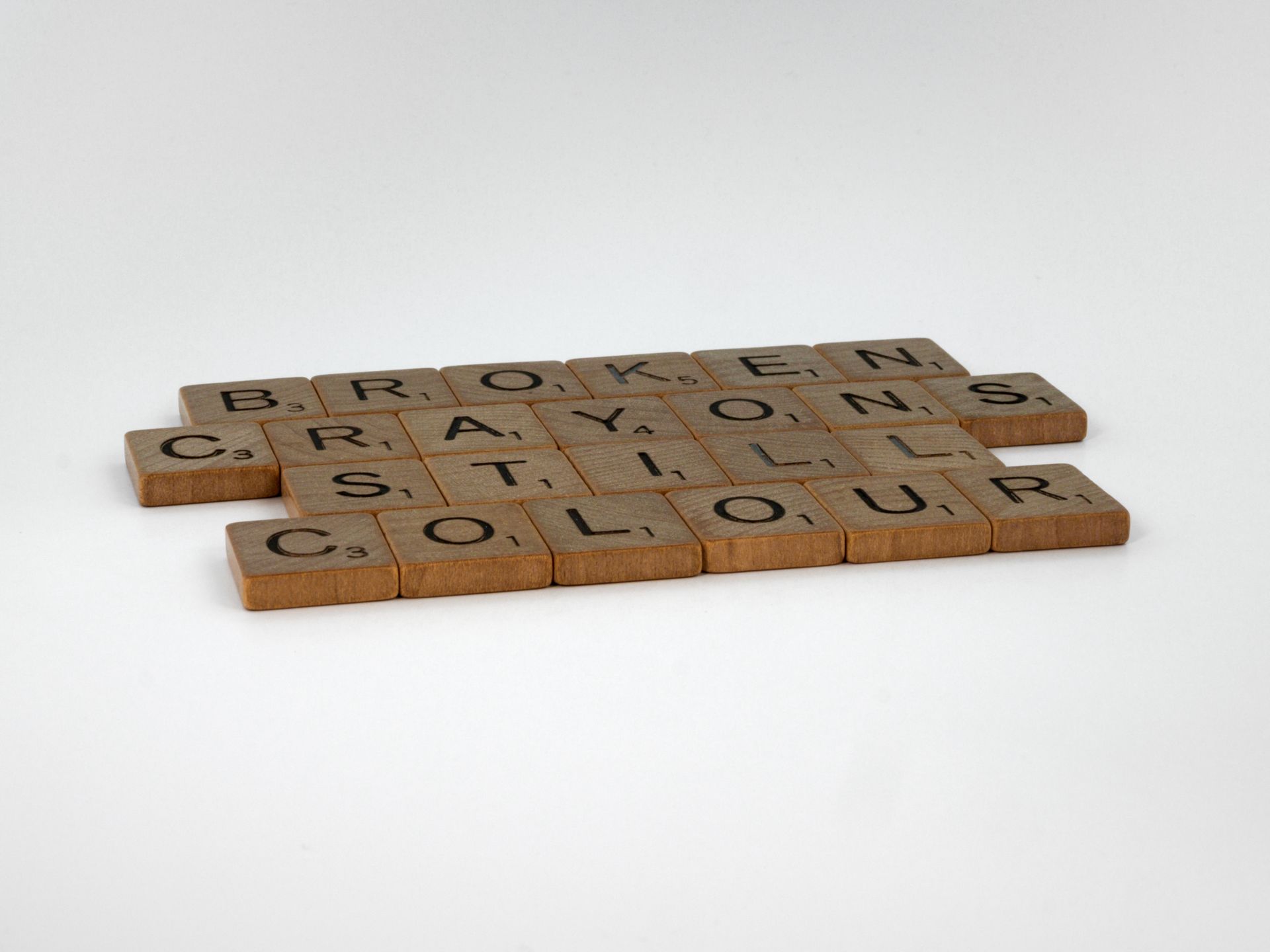 Scrabble tiles spelling Broken Crayons Still Colour on white