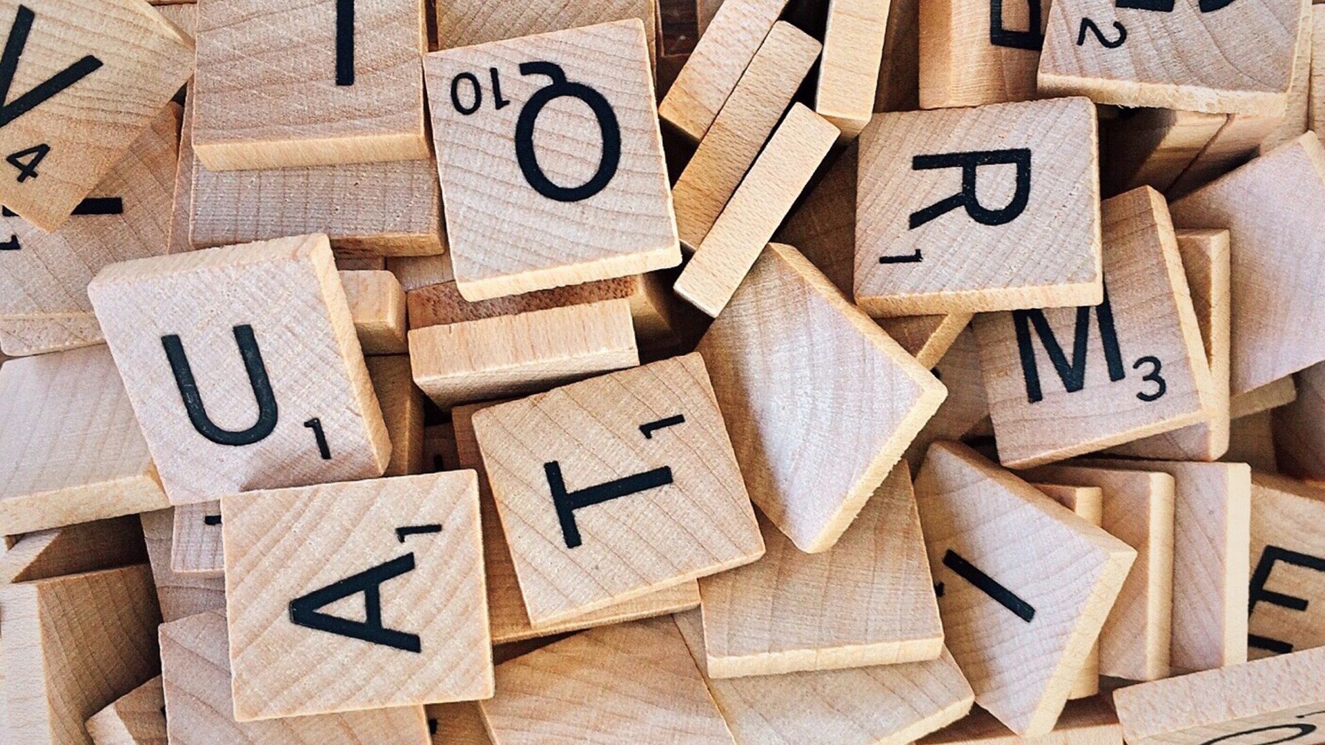Close-up pile of wooden Scrabble letter tiles showing letters and numbers