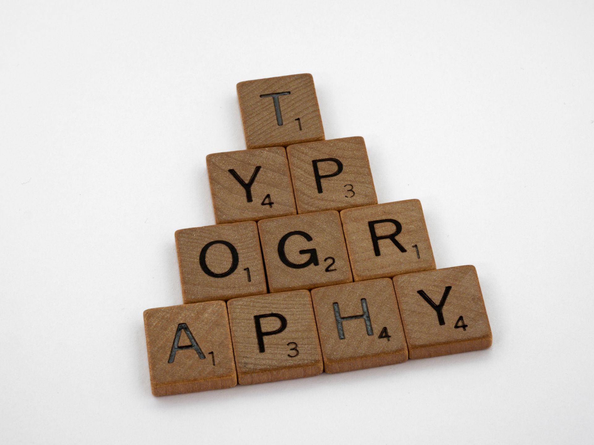 Close-up of wooden Scrabble tiles showing letter faces and scores