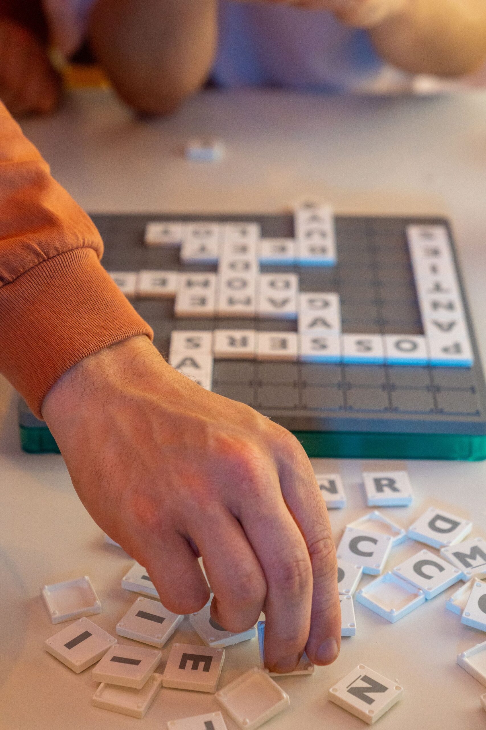 Hand placing Scrabble tiles on the board during a game
