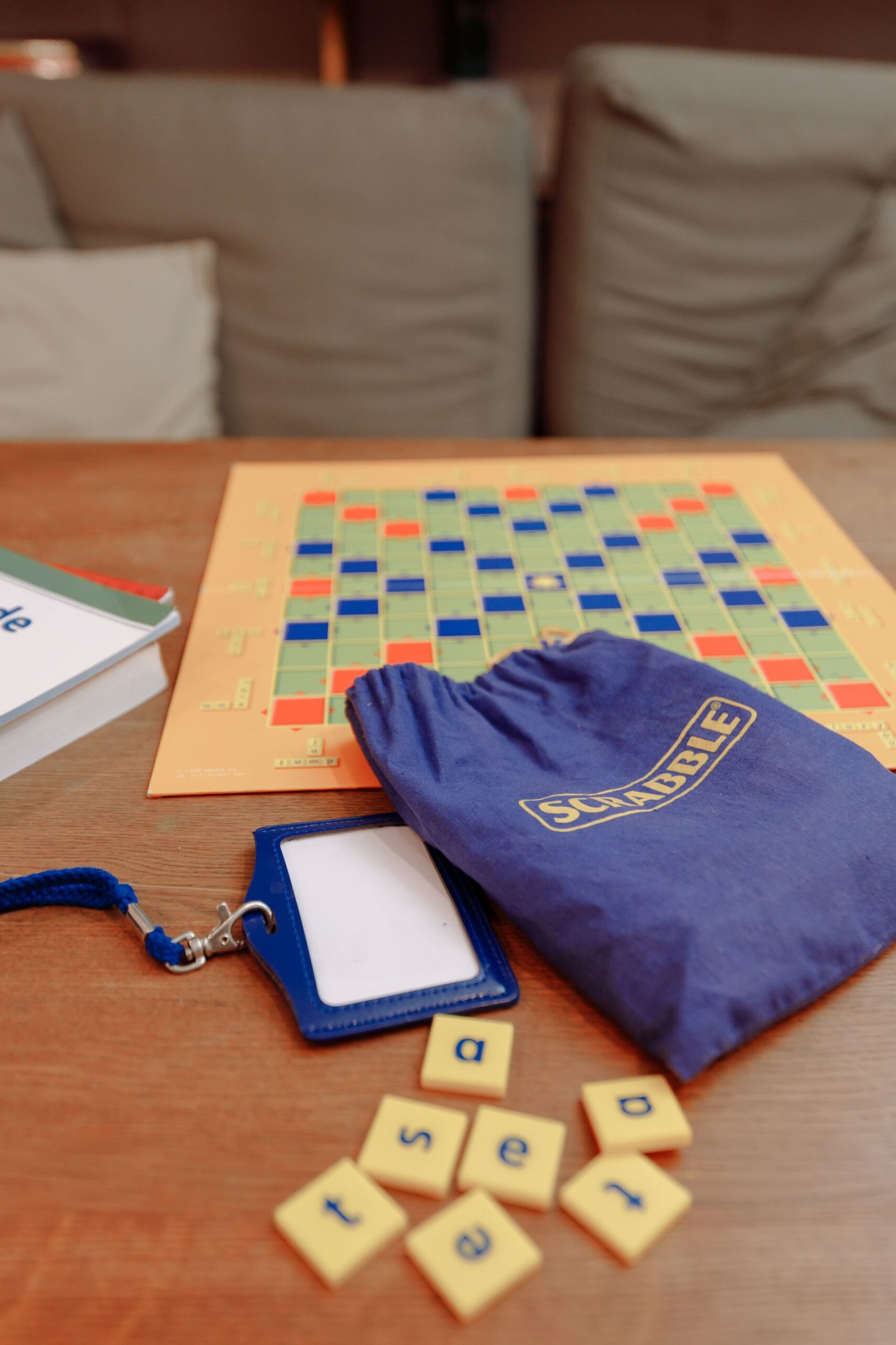 Scrabble board game setup with tiles and tile bag on a wooden table