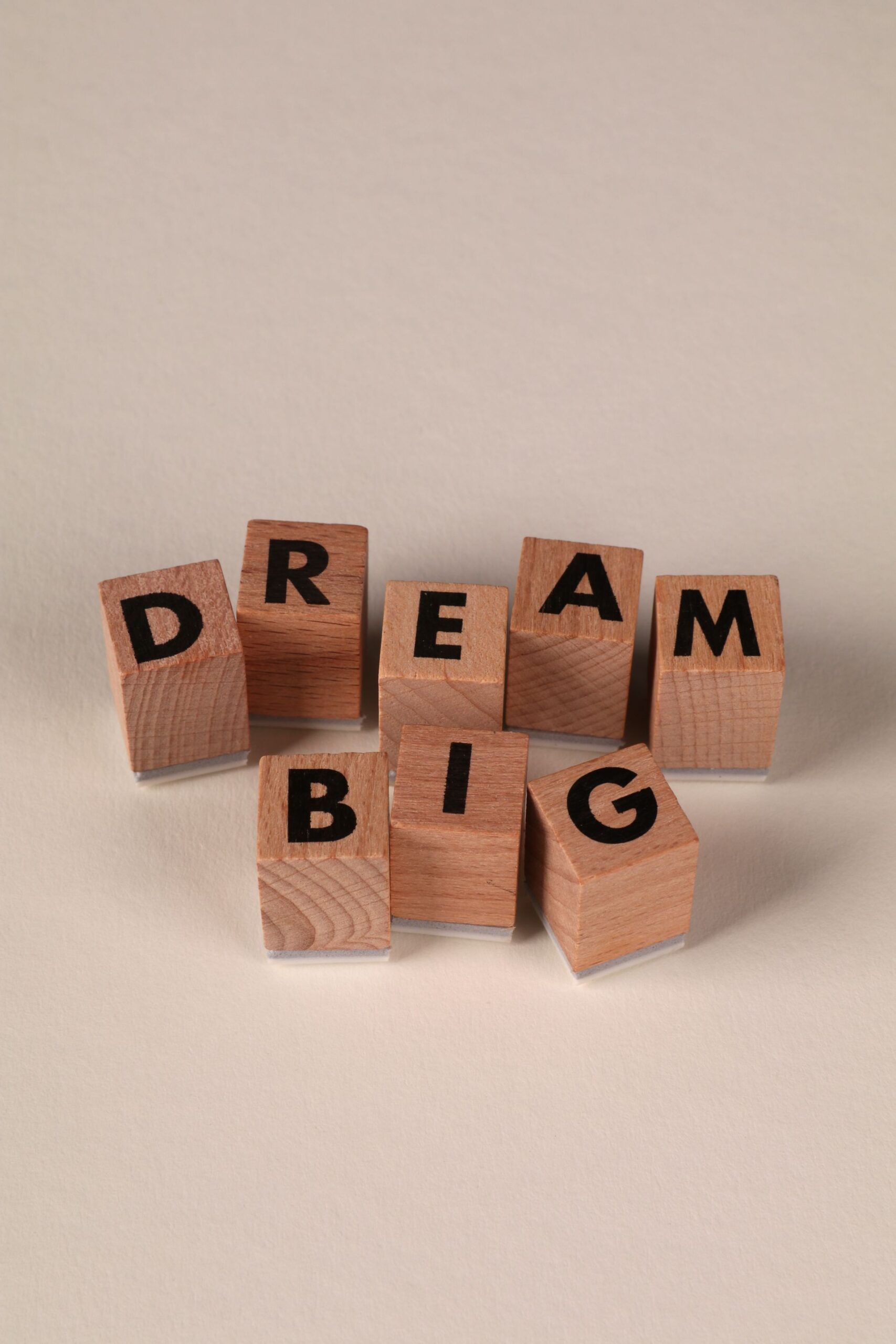 Wooden blocks spelling Dream Big on a neutral background