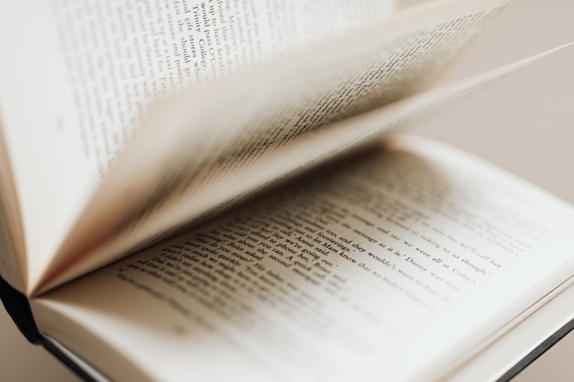 Open book lying on a table beside a coffee cup