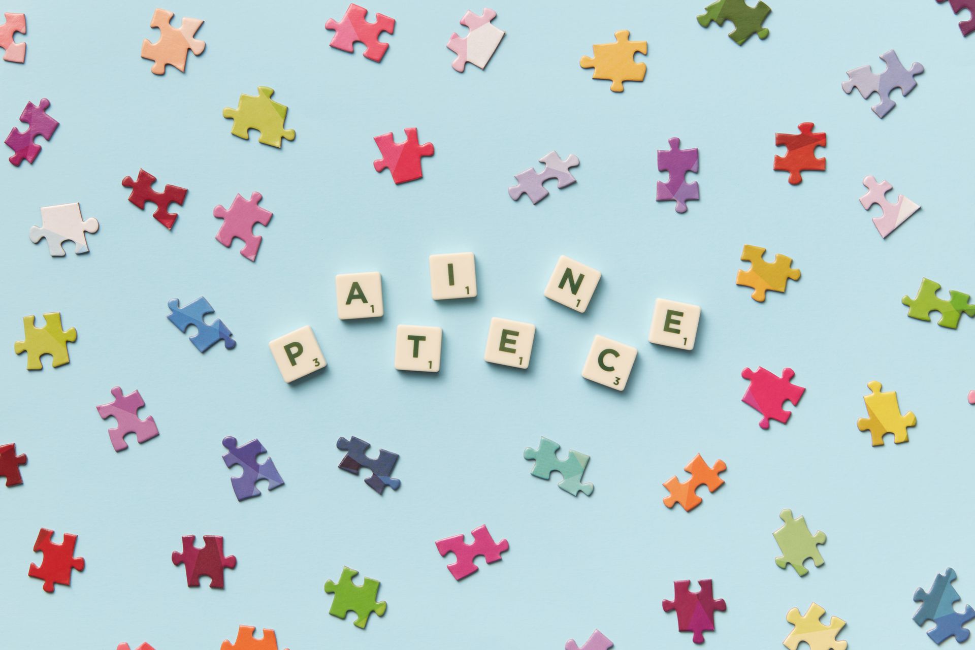 Scrabble letters and puzzle pieces on a light blue background